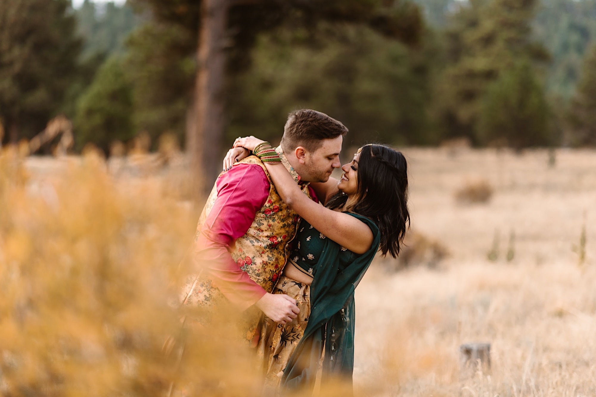 An Indian elopement couple stands in a field near Denver, Colorado as they snuggle up together. Photo by Denver elopement photographer, Colorado elopement photographer, Ashley Joyce Photography.