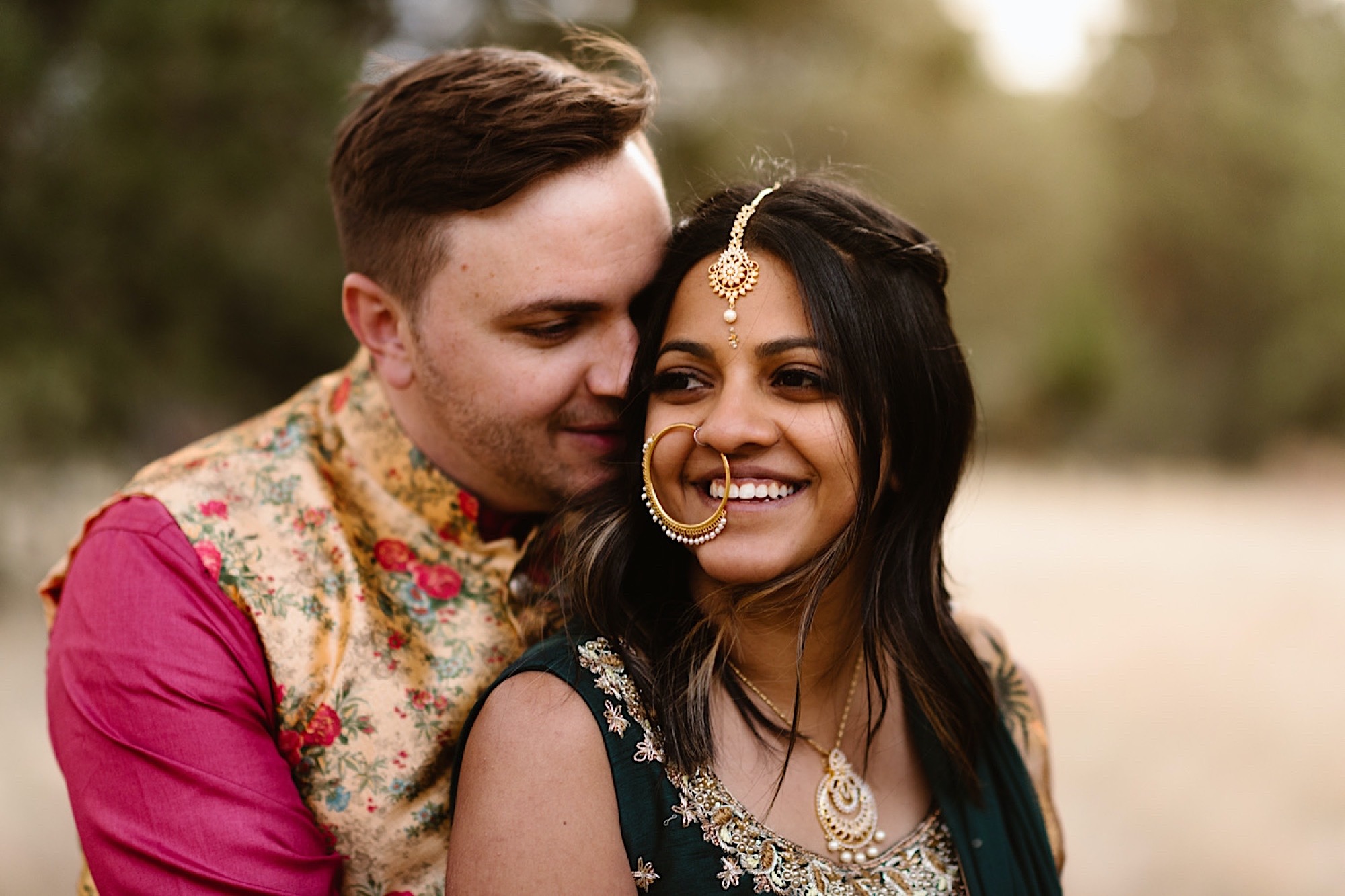 An Indian wedding couple stands in a field near Denver, Colorado as they snuggle up together. Photo by Denver elopement photographer, Colorado elopement photographer, Ashley Joyce Photography.