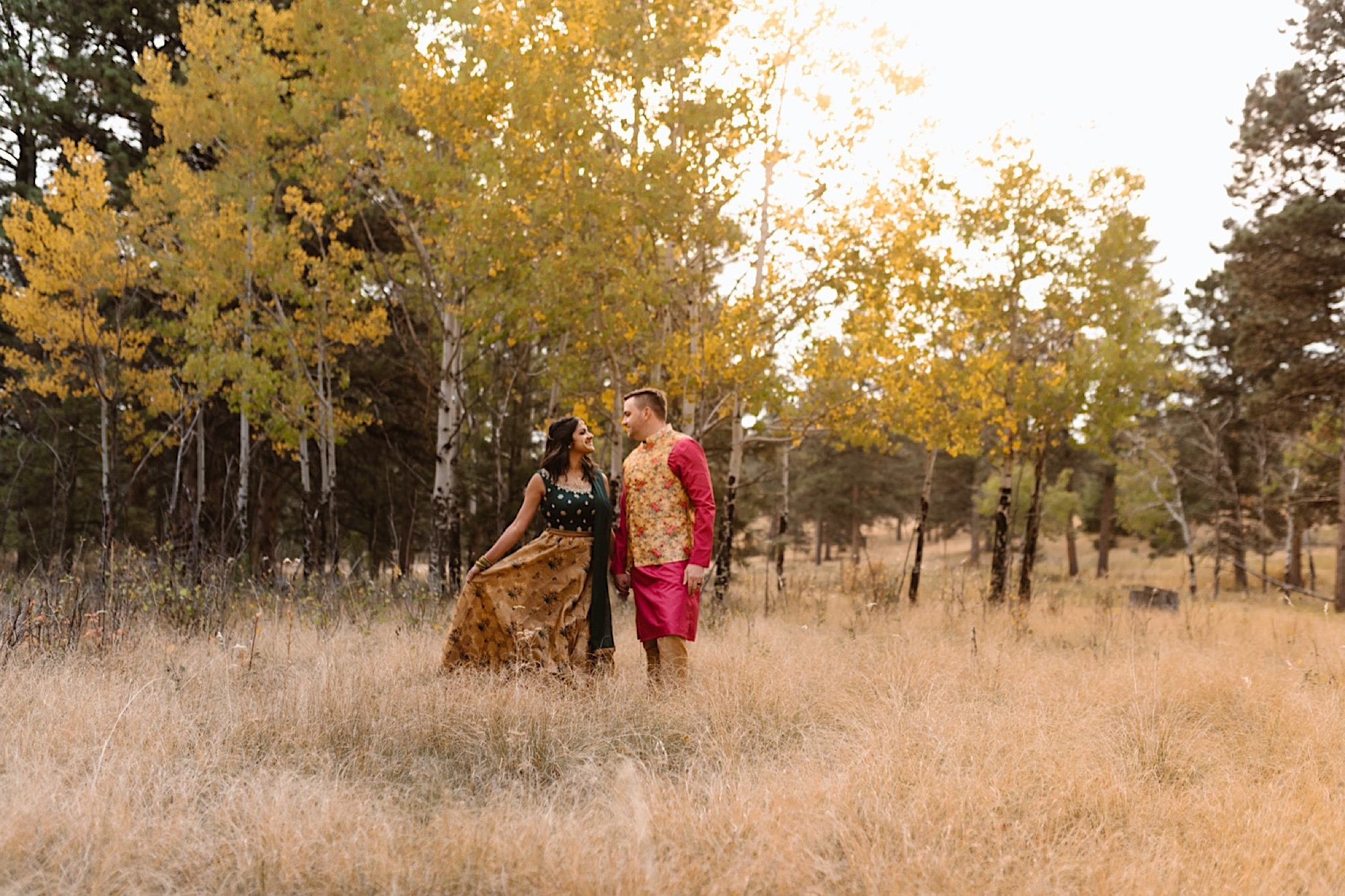 An Indian wedding couple stands in a field of colorful aspens near Denver, Colorado as they snuggle up together for their Indian elopement photos. Photo by Denver elopement photographer, Colorado elopement photographer, Ashley Joyce Photography.
