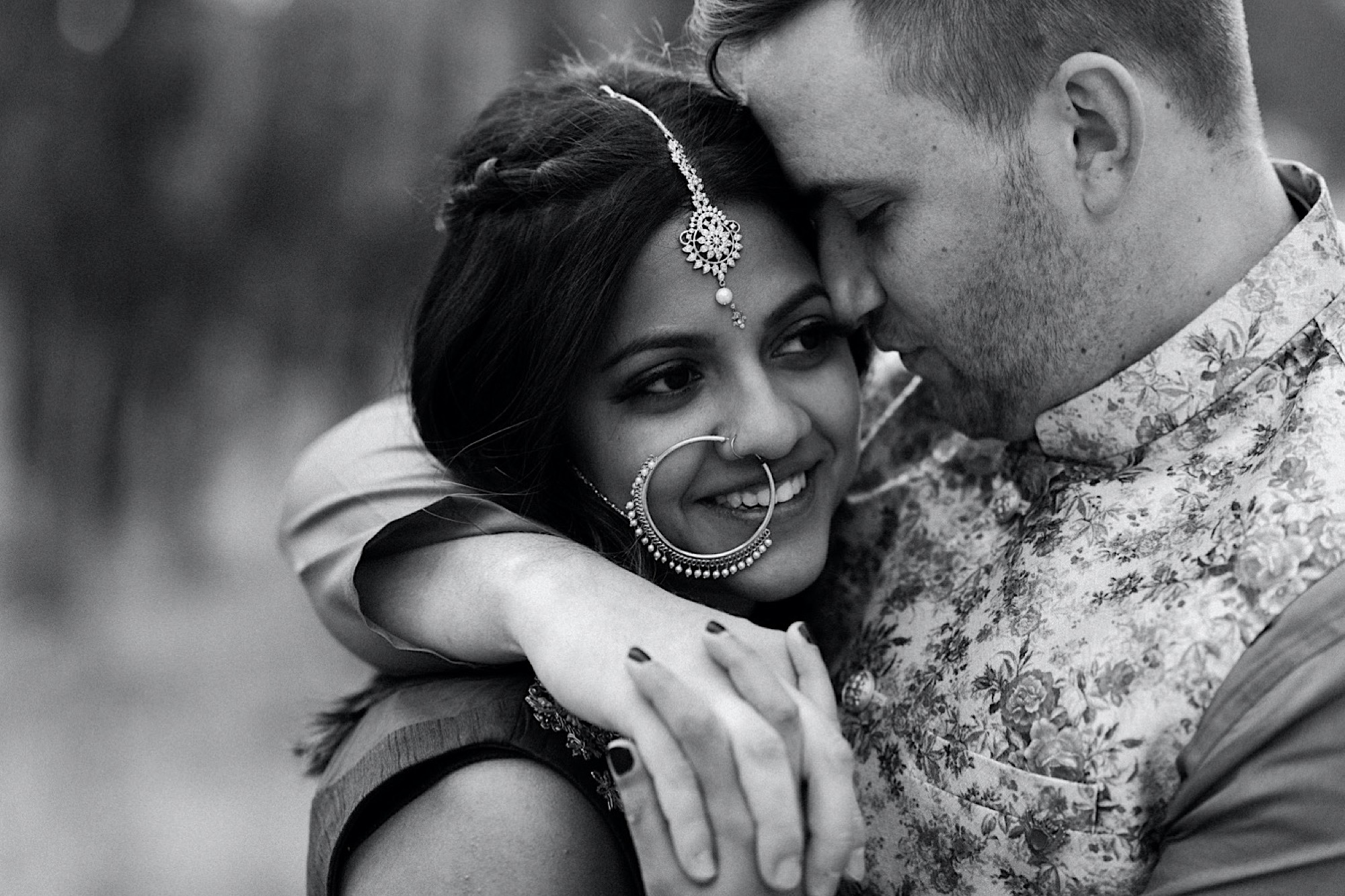 Black and white image of a Colorado Indian elopement couple as they stand in a field of aspen trees near Denver, Colorado. This image shows a closeup of the couple with the groom’s arm around his bride’s shoulder. Photo by Denver elopement photographer, Colorado elopement photographer, Ashley Joyce Photography.