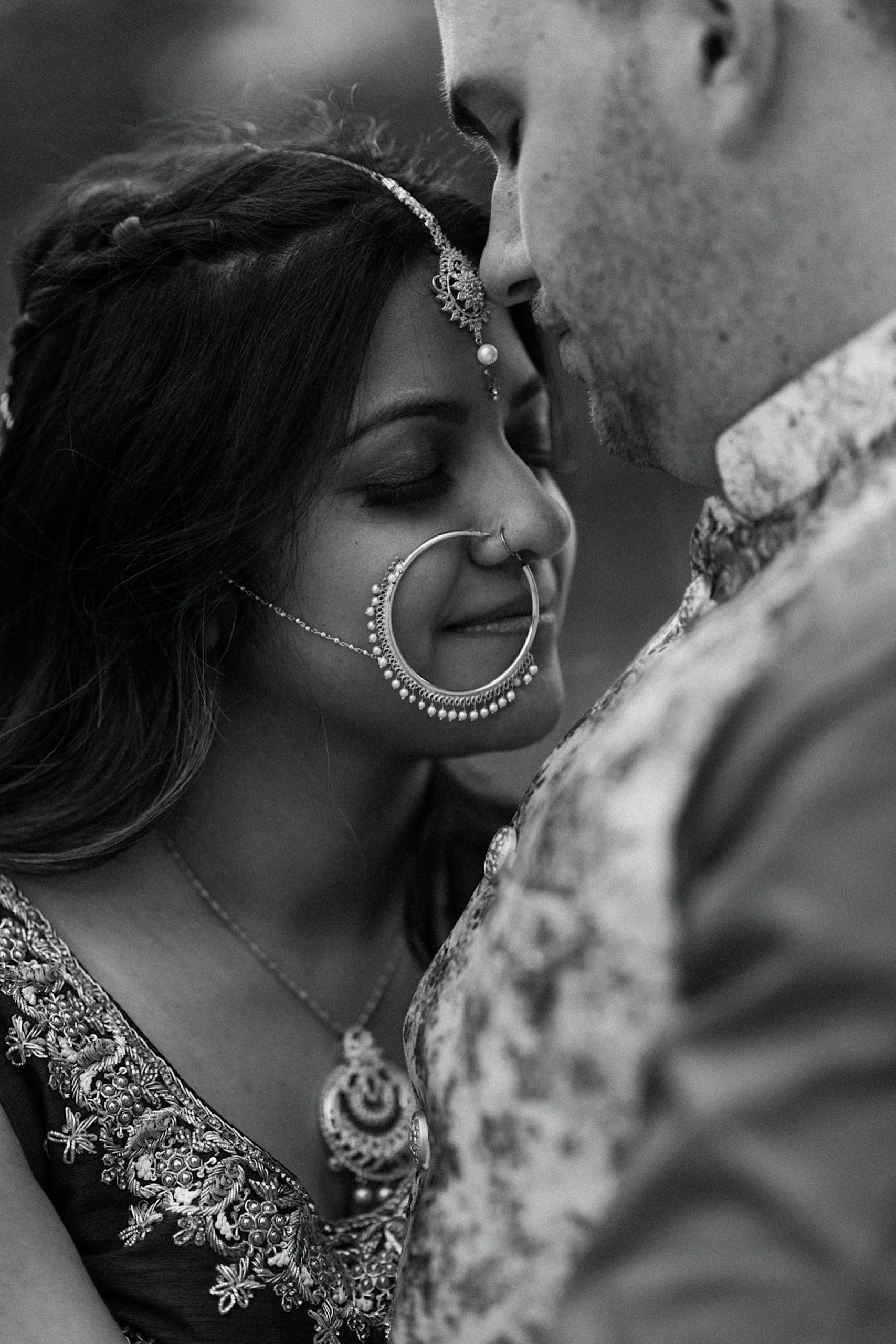 Black and white image of a Colorado Indian elopement couple as they stand in a field of aspen trees near Denver, Colorado as they snuggle up together for their Indian elopement photos. Photo by Denver elopement photographer, Colorado elopement photographer, Ashley Joyce Photography.