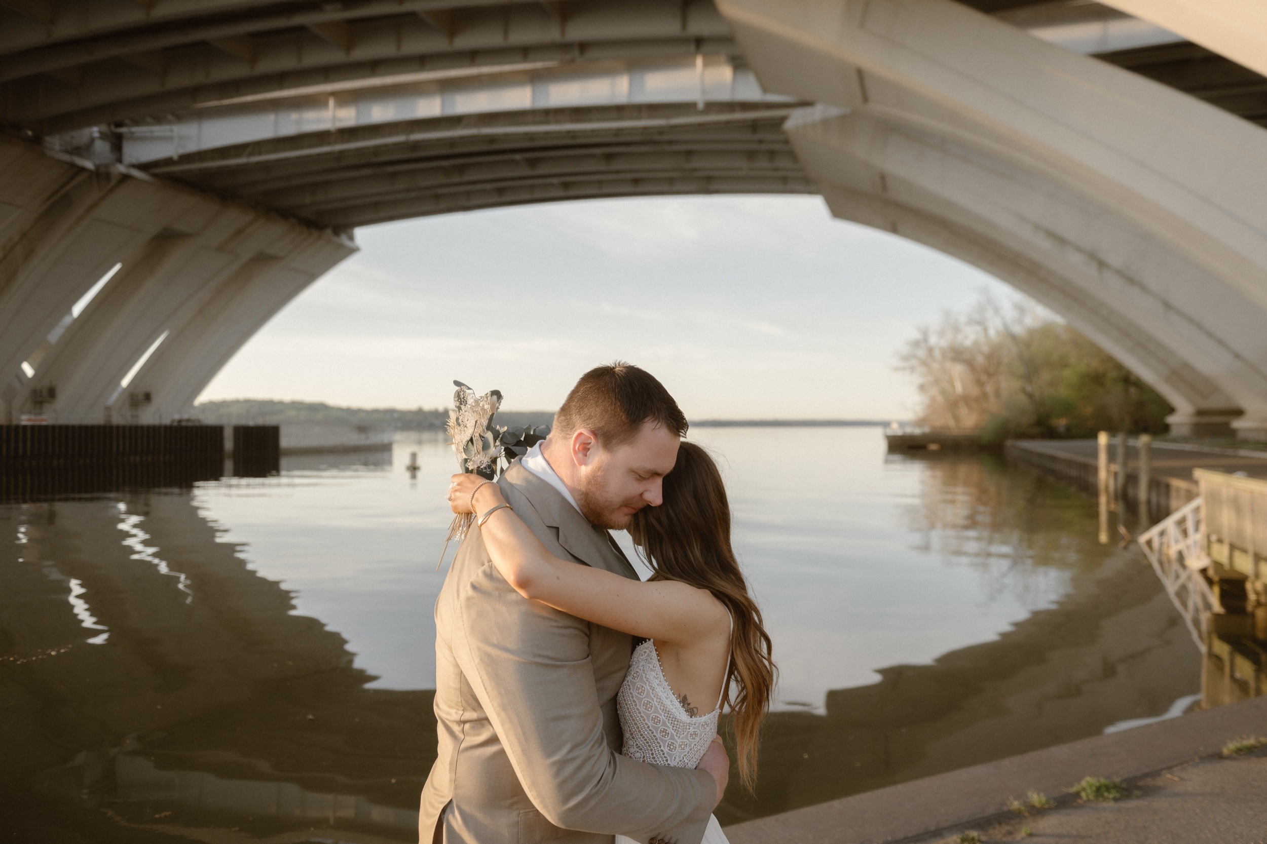 A married couple poses for their Alexandria, Virginia wedding anniversary photo session at Jones Point Park with Colorado photographer, Ashley Joyce Photography. Copyright Ashley Joyce Photography 2022.
