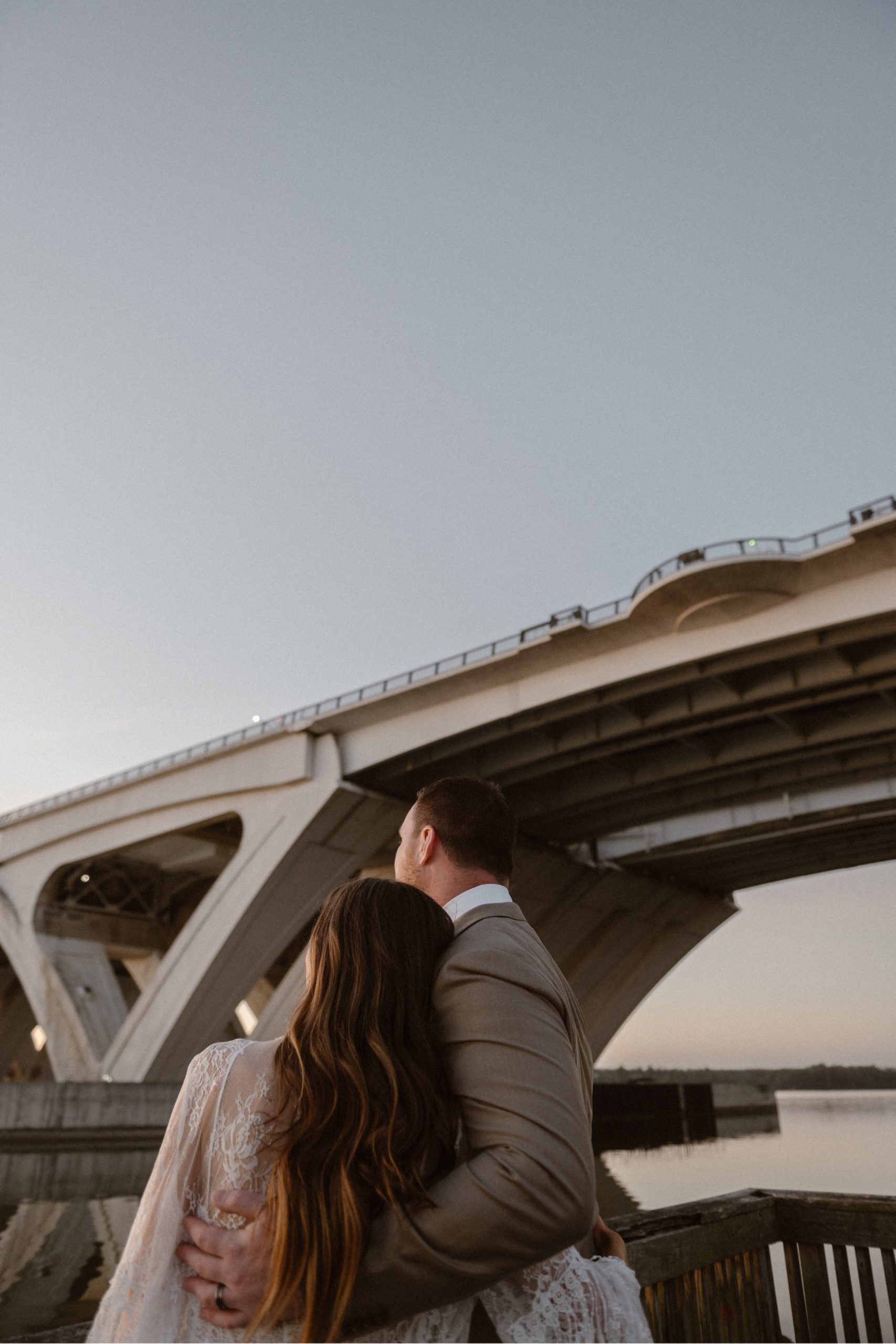 A married couple poses for their Alexandria, Virginia wedding anniversary photo session at Jones Point Park with Colorado photographer, Ashley Joyce Photography. Copyright Ashley Joyce Photography 2022.