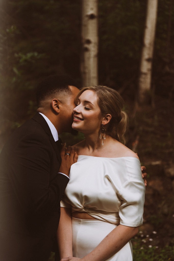 Bride and groom snuggling in the woods | Wedding portraits | Elopement portraits | Bride and groom elopement photos | Elopement wedding photos in Colorado | Colorado wedding photos | Colorado elopement photos | Elopement at Treehaus, Colorado | Treehaus Colorado | Colorado elopement | Treehaus elopement | Colorado elopement venue | Colorado mountain elopement venue | Unique elopement venue | Elopement venue in Colorado | Ashley Joyce Photography 2020