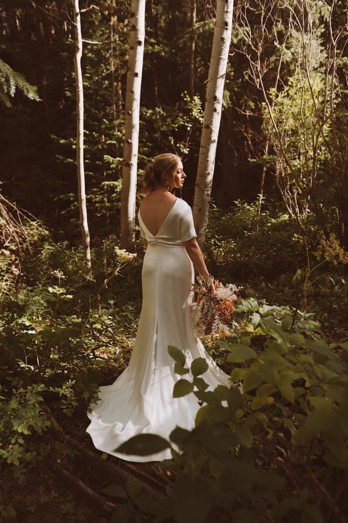 Bride standing in the woods of Colorado at Treehaus Colorado | Wedding portraits | Elopement portraits | Bride and groom elopement photos | Elopement wedding photos in Colorado | Colorado wedding photos | Colorado elopement photos | Elopement at Treehaus, Colorado | Treehaus Colorado | Colorado elopement | Treehaus elopement | Colorado elopement venue | Colorado mountain elopement venue | Unique elopement venue | Elopement venue in Colorado | Ashley Joyce Photography 2020