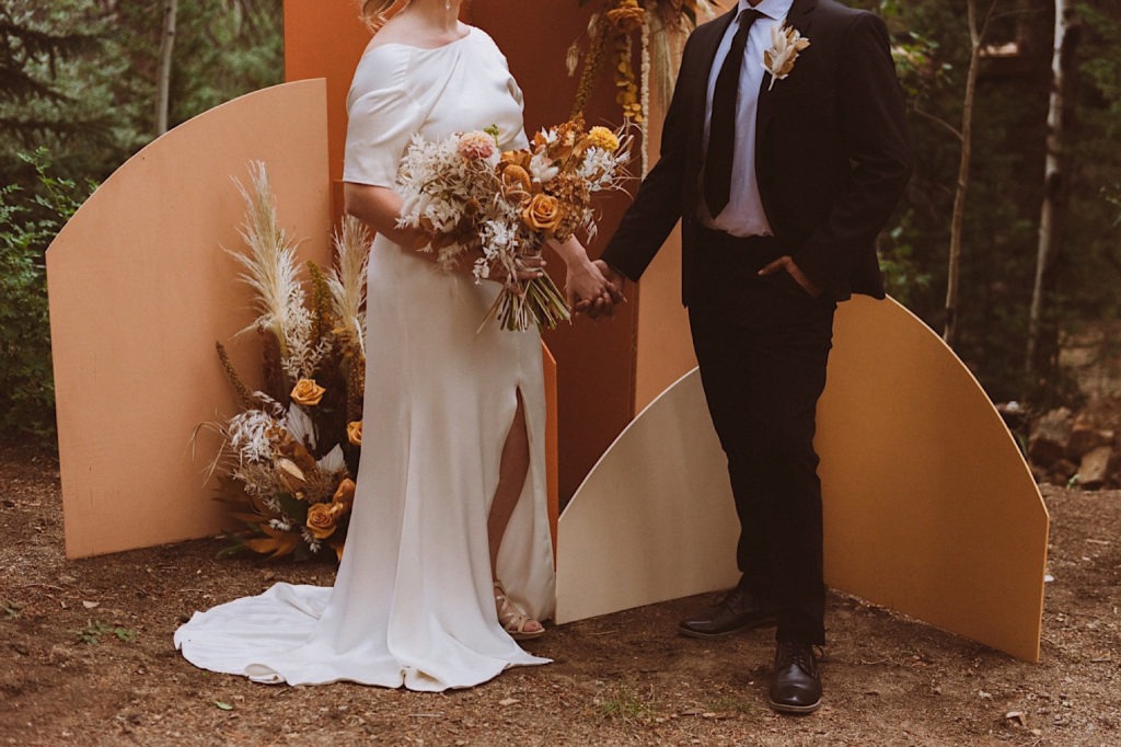 Bride and groom standing in front of a floral and wood arch in the forest | Floral arch detail | Elopement decor | Wedding decor | Wedding portraits | Elopement portraits | Bride and groom elopement photos | Elopement wedding photos in Colorado | Colorado wedding photos | Colorado elopement photos | Elopement at Treehaus, Colorado | Treehaus Colorado | Colorado elopement | Treehaus elopement | Colorado elopement venue | Colorado mountain elopement venue | Unique elopement venue | Elopement venue in Colorado | Ashley Joyce Photography 2020
