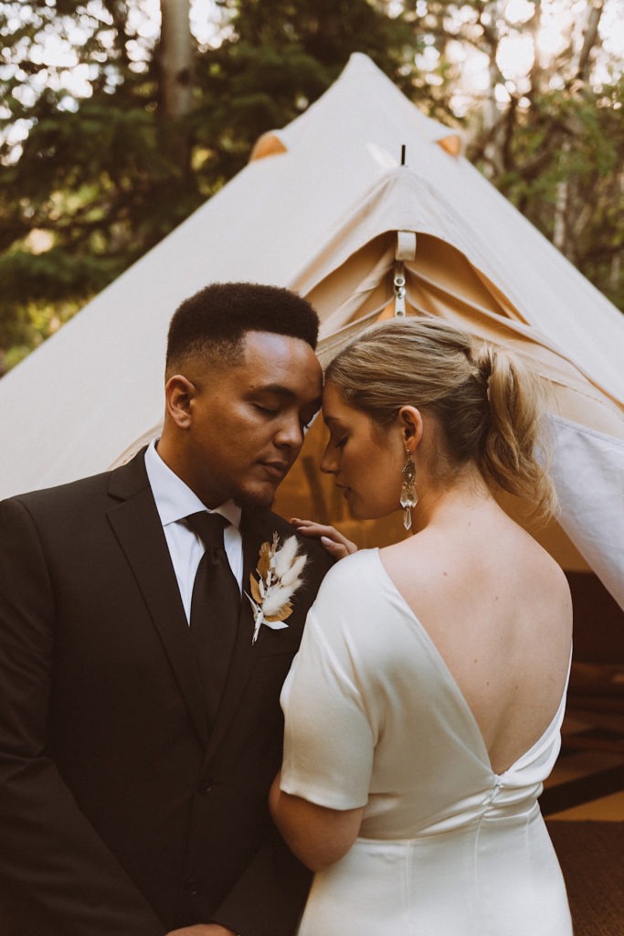 Bride and groom snuggling in front of wedding tent at Treehaus Colorado | Wedding portraits | Elopement portraits | Bride and groom elopement photos | Elopement wedding photos in Colorado | Colorado wedding photos | Colorado elopement photos | Elopement at Treehaus, Colorado | Treehaus Colorado | Colorado elopement | Treehaus elopement | Colorado elopement venue | Colorado mountain elopement venue | Unique elopement venue | Elopement venue in Colorado | Ashley Joyce Photography 2020