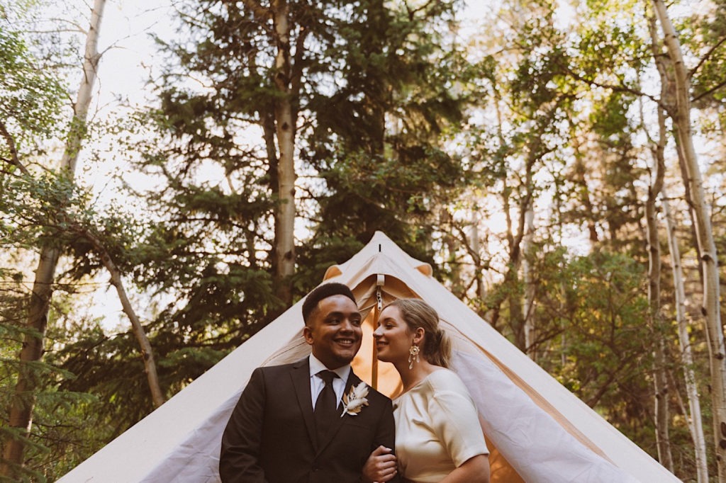 Bride and groom laughing together in front of wedding tent at Treehaus Colorado | Wedding portraits | Elopement portraits | Bride and groom elopement photos | Elopement wedding photos in Colorado | Colorado wedding photos | Colorado elopement photos | Elopement at Treehaus, Colorado | Treehaus Colorado | Colorado elopement | Treehaus elopement | Colorado elopement venue | Colorado mountain elopement venue | Unique elopement venue | Elopement venue in Colorado | Ashley Joyce Photography 2020