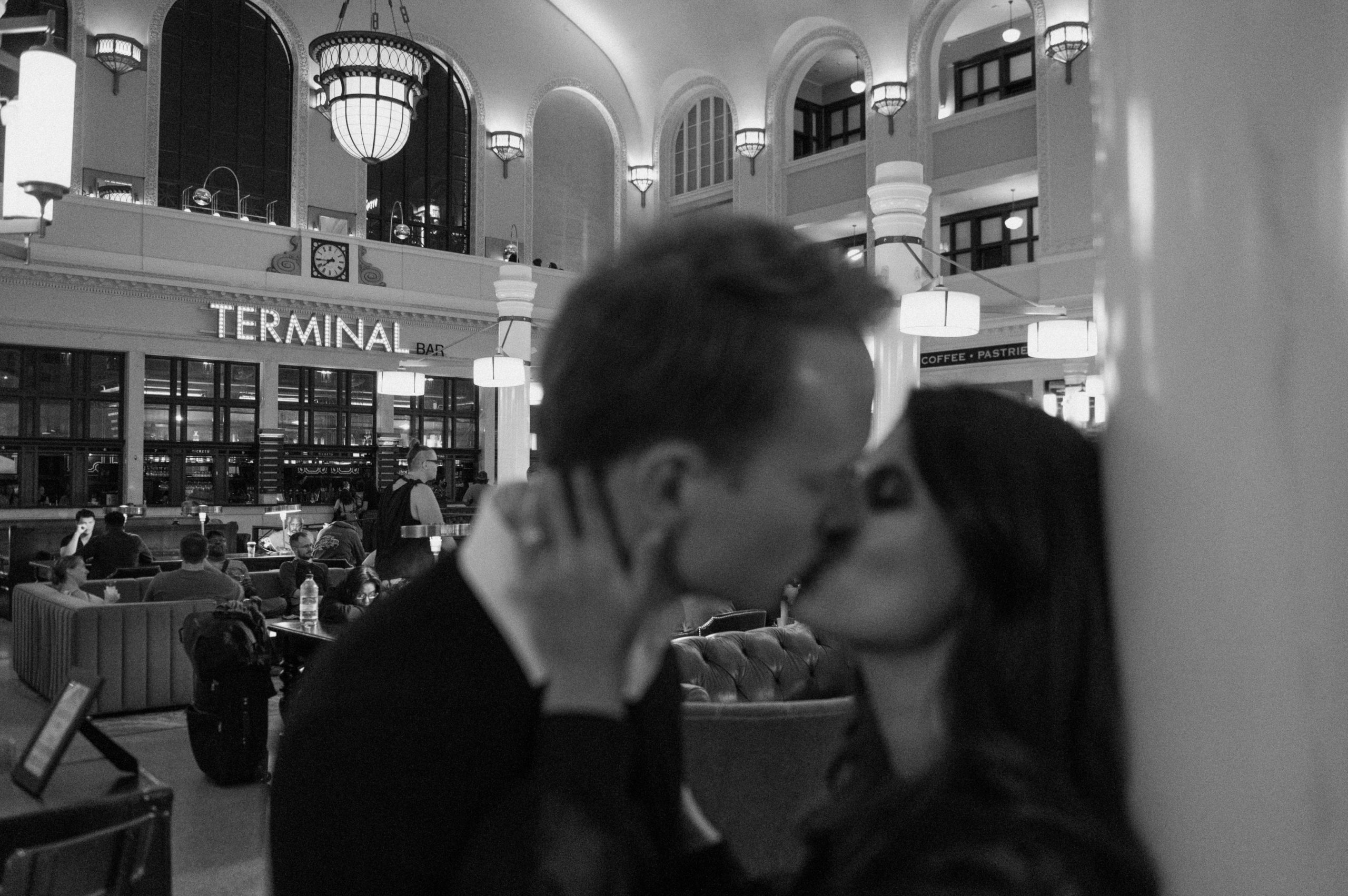 Black and white photo of a Denver couple posing for their Downtown Denver engagement session in Union Station. Photo by Denver elopement photographer, Ashley Joyce Photography. Copyright, 2022.