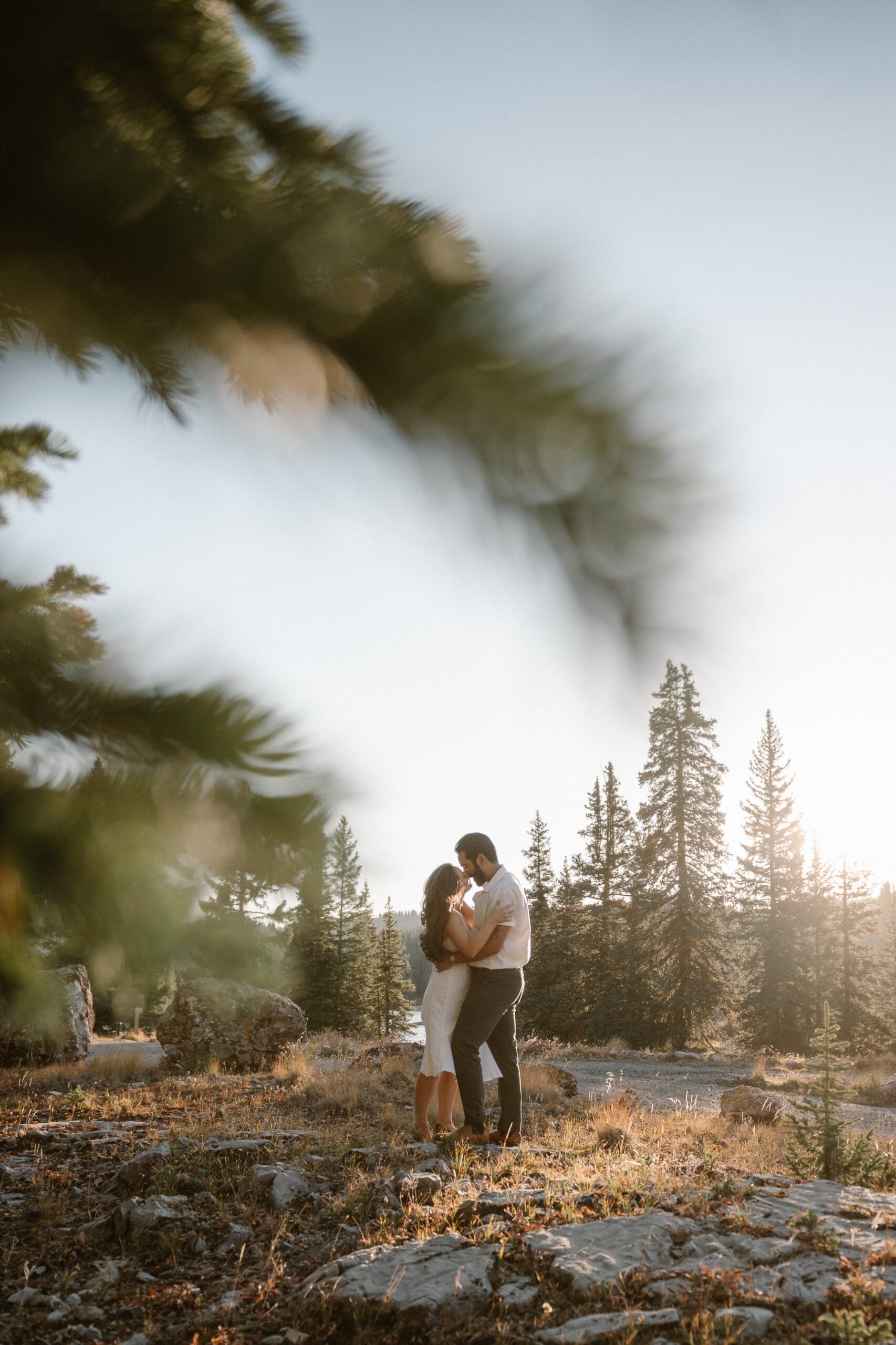 An engaged couple enjoying an intimate moment outdoors in a forest setting at Molas Lake in Colorado, during sunset. Photo by Colorado wedding photographer Ashley Joyce.