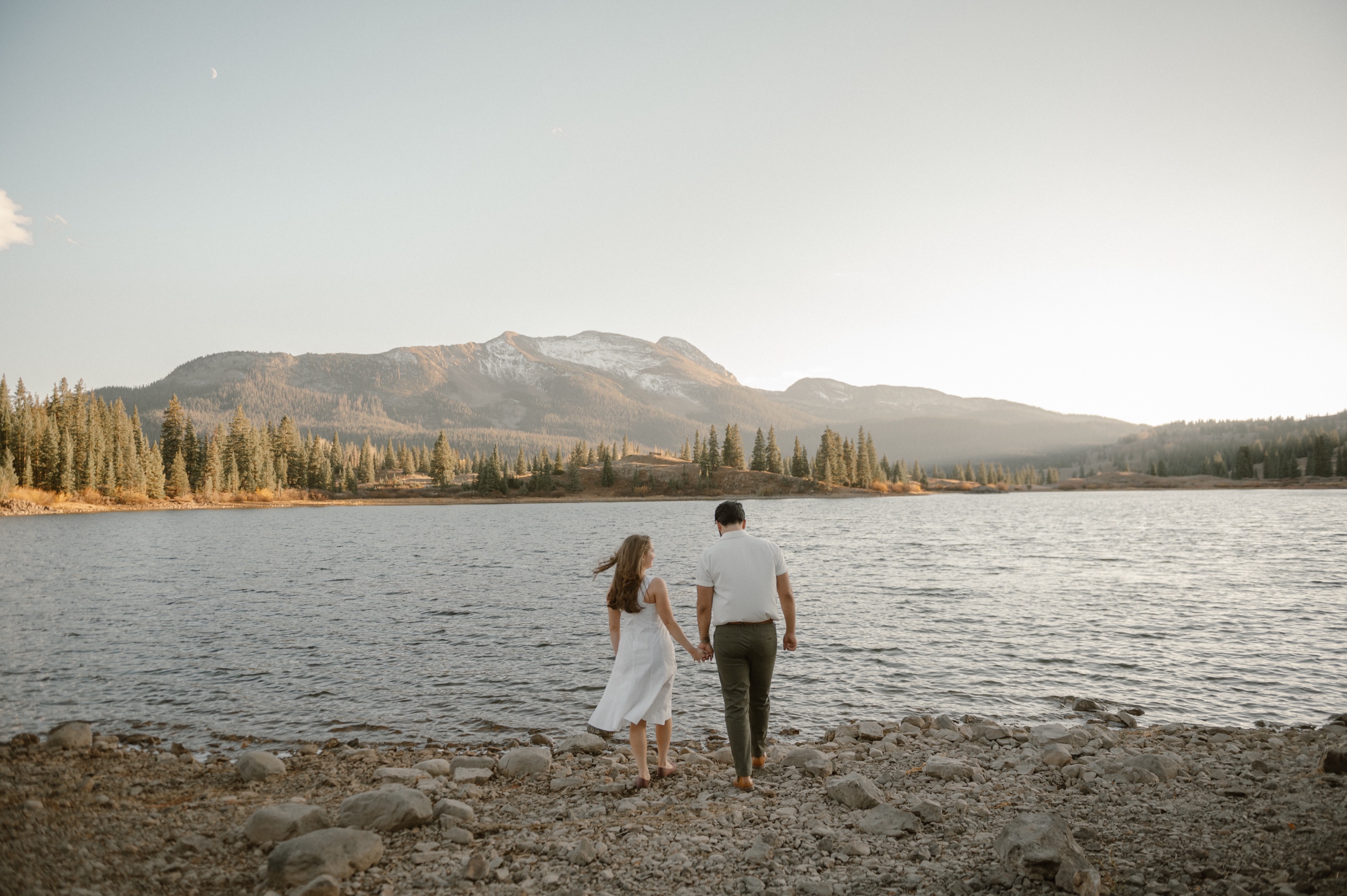 An engaged couple enjoying an intimate moment outdoors in a forest setting at Molas Lake in Colorado, during sunset. Photo by Colorado wedding photographer Ashley Joyce.