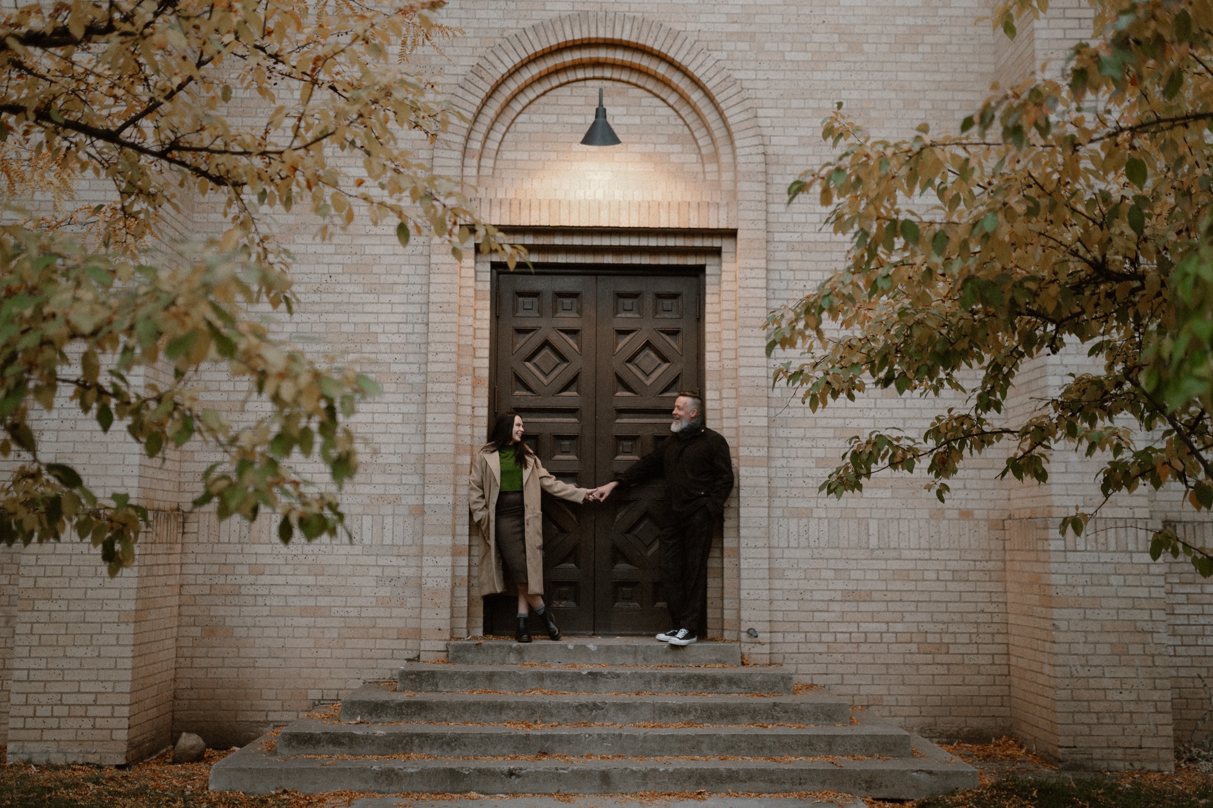 A color photo of an engaged couple holding hands in front of The Smiley Building in Durango, Colorado during the fall for their engagement session, taken by Colorado wedding photographer, Ashley Joyce.