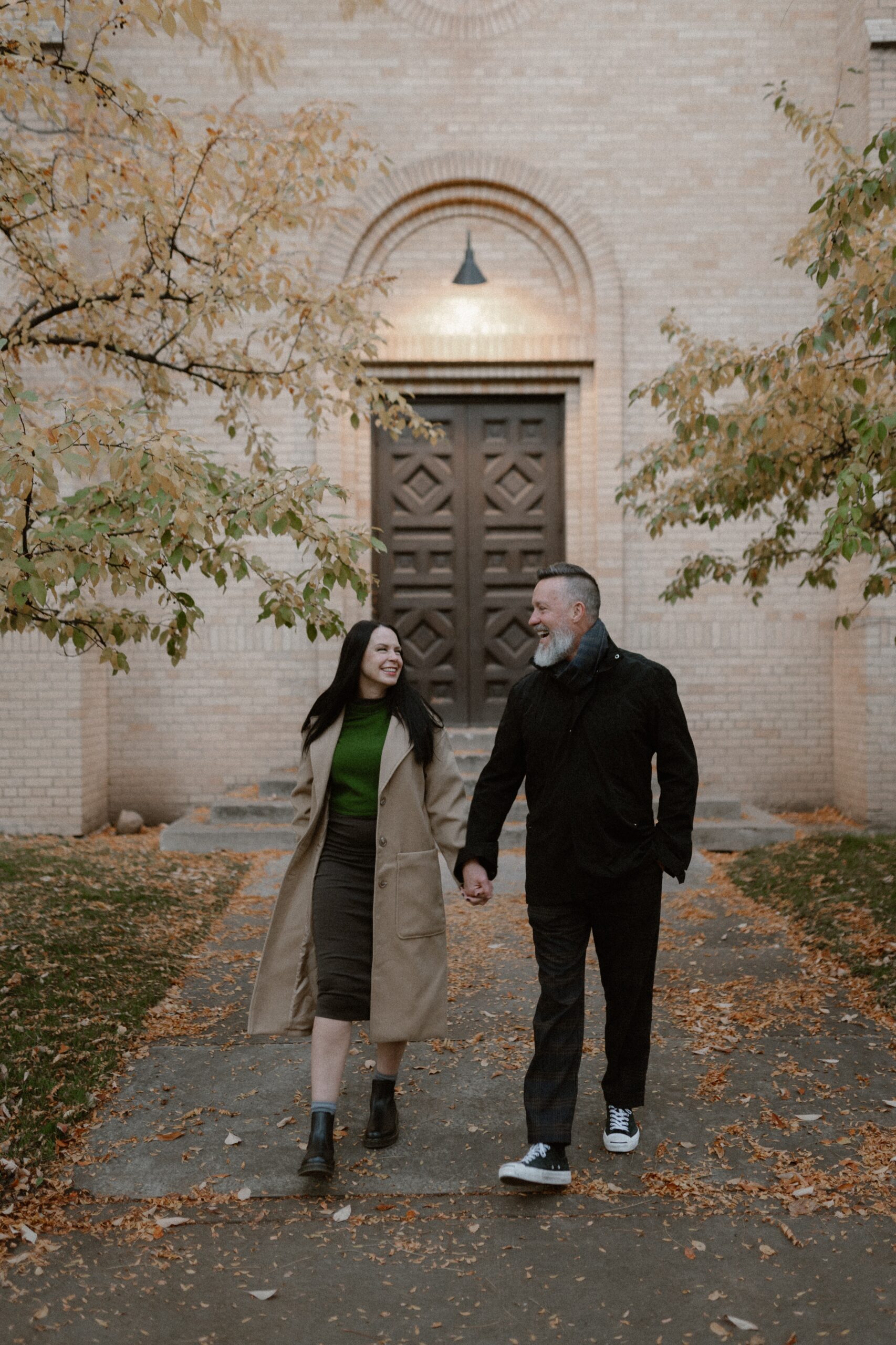 A color photo of an engaged couple holding hands in front of The Smiley Building in Durango, Colorado during the fall for their engagement session, taken by Colorado wedding photographer, Ashley Joyce.