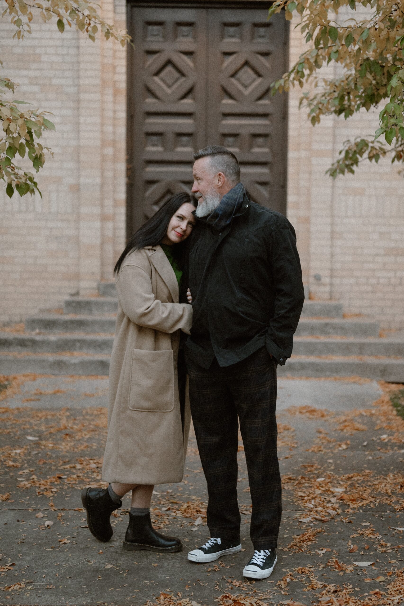 A color photo of an engaged couple embracing one another in front of the Smiley Building for their Durango engagement session. Photo by Colorado wedding photographer Ashley Joyce.