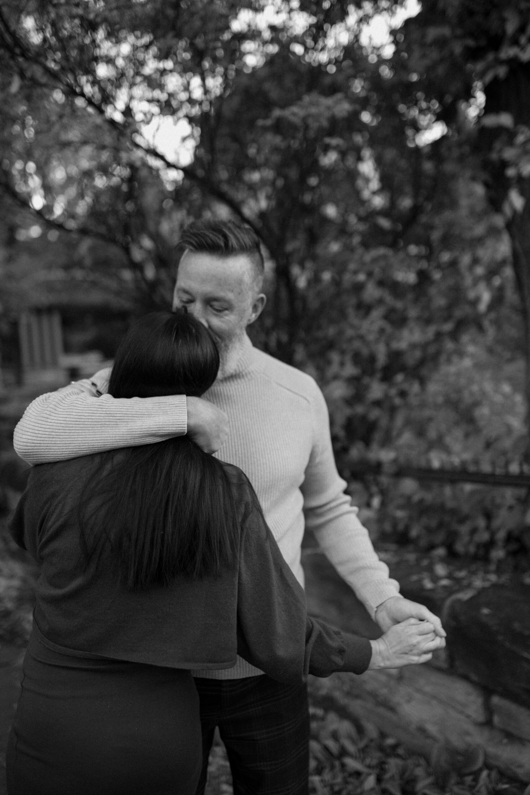A black and white photo of a man kissing his fiance's forehead while he embraces her for their Durango, Colorado engagement session. Photo by Ashley Joyce.