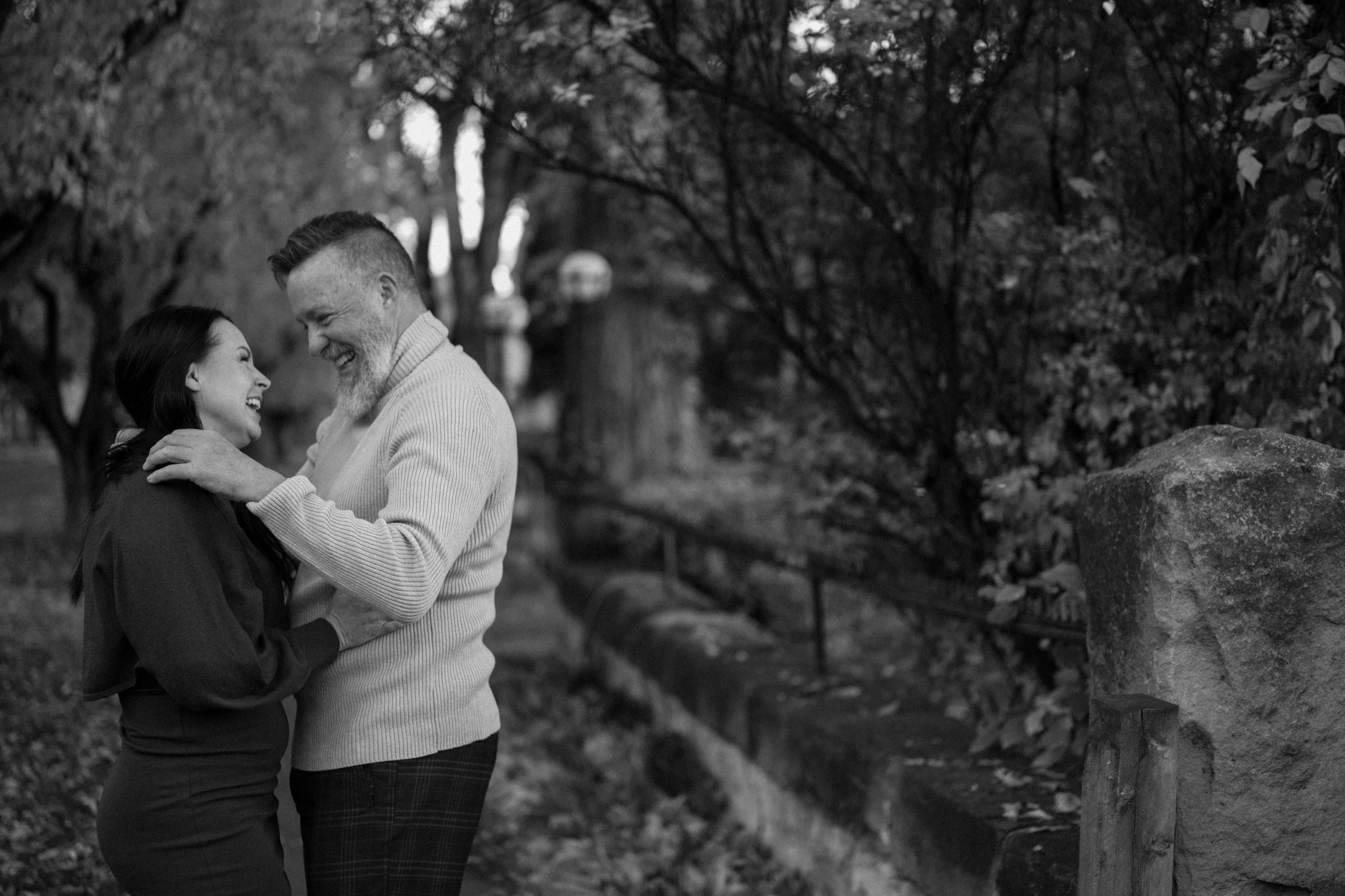 A black and white photo of an engaged couple laughing together while they hold one another for their engagement session in Durango, Colorado. Photo by Ashley Joyce.
