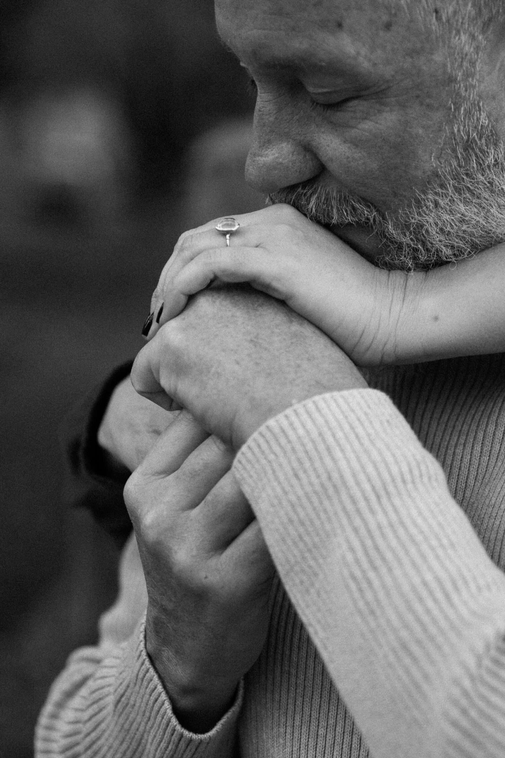 A closeup of a man kissing his fiance's hand while he embraces her for their Durango engagement session. Photo by Ashley Joyce.