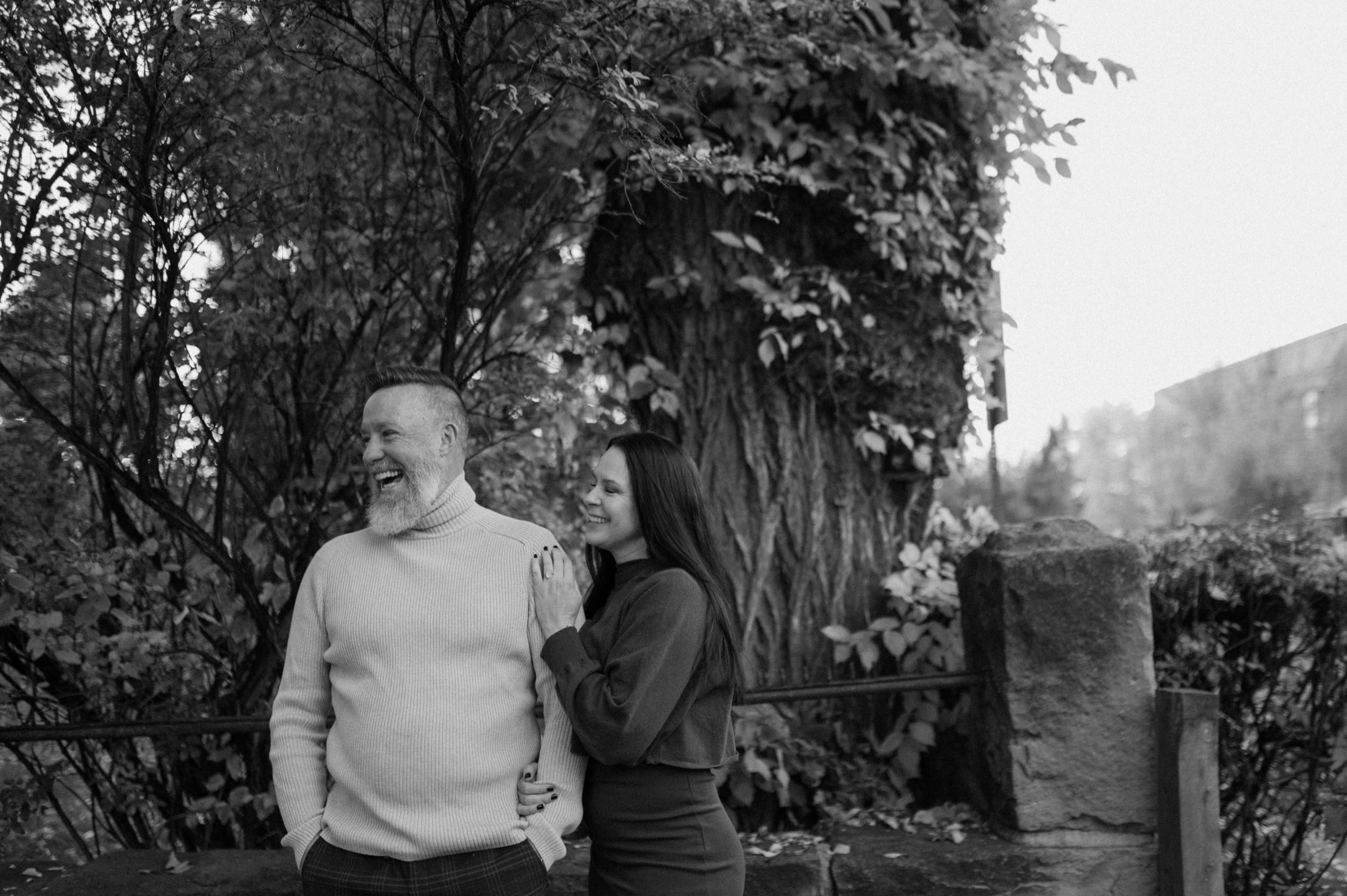 A black and white photo of a couple laughing together in Downtown Durango for their engagement session. Photo by Ashley Joyce