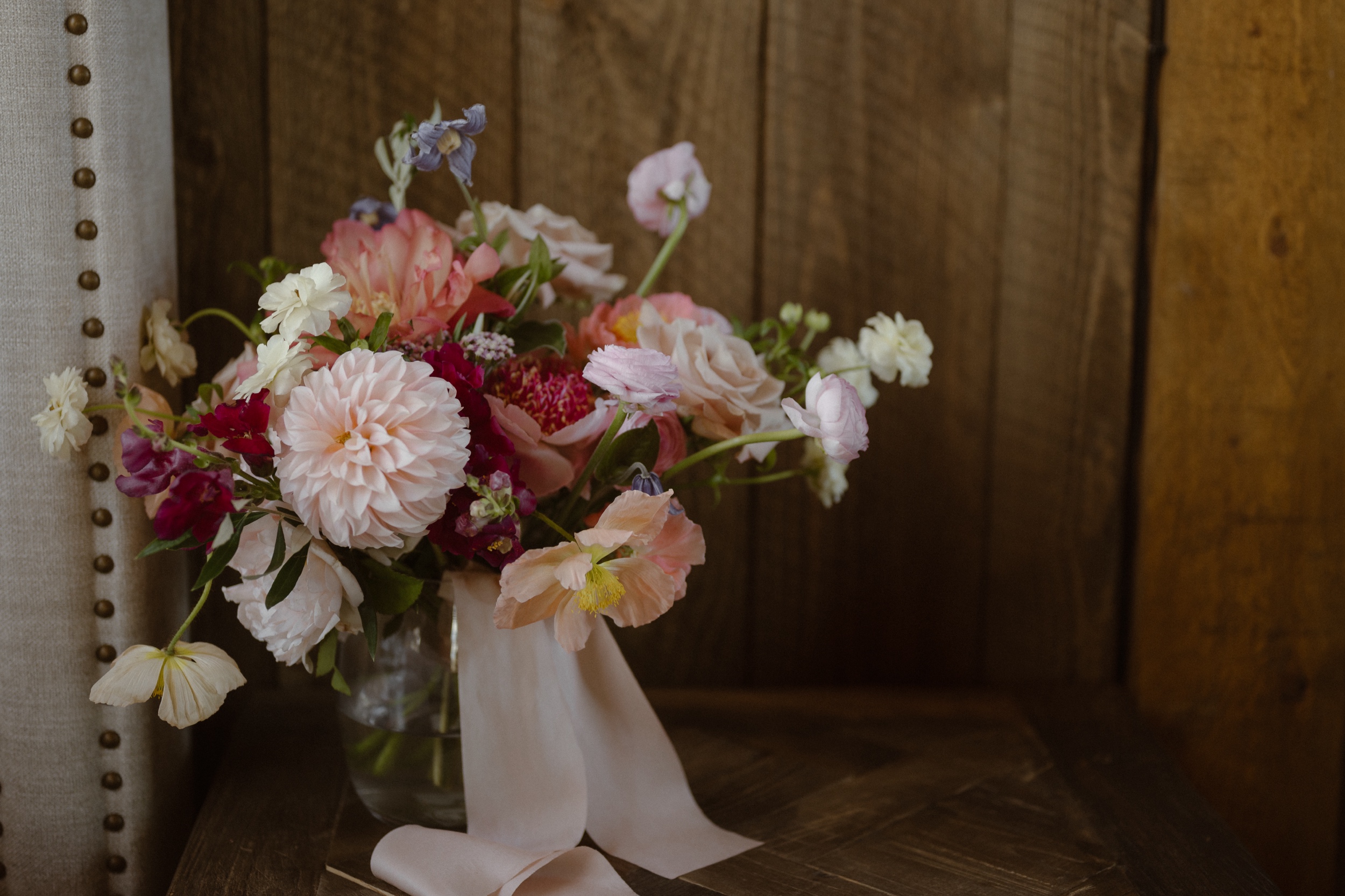 A photo of a bride's pink and white wedding bouquet set in a glass vase at Three Peaks Ranch. Photo by Ashley Joyce.