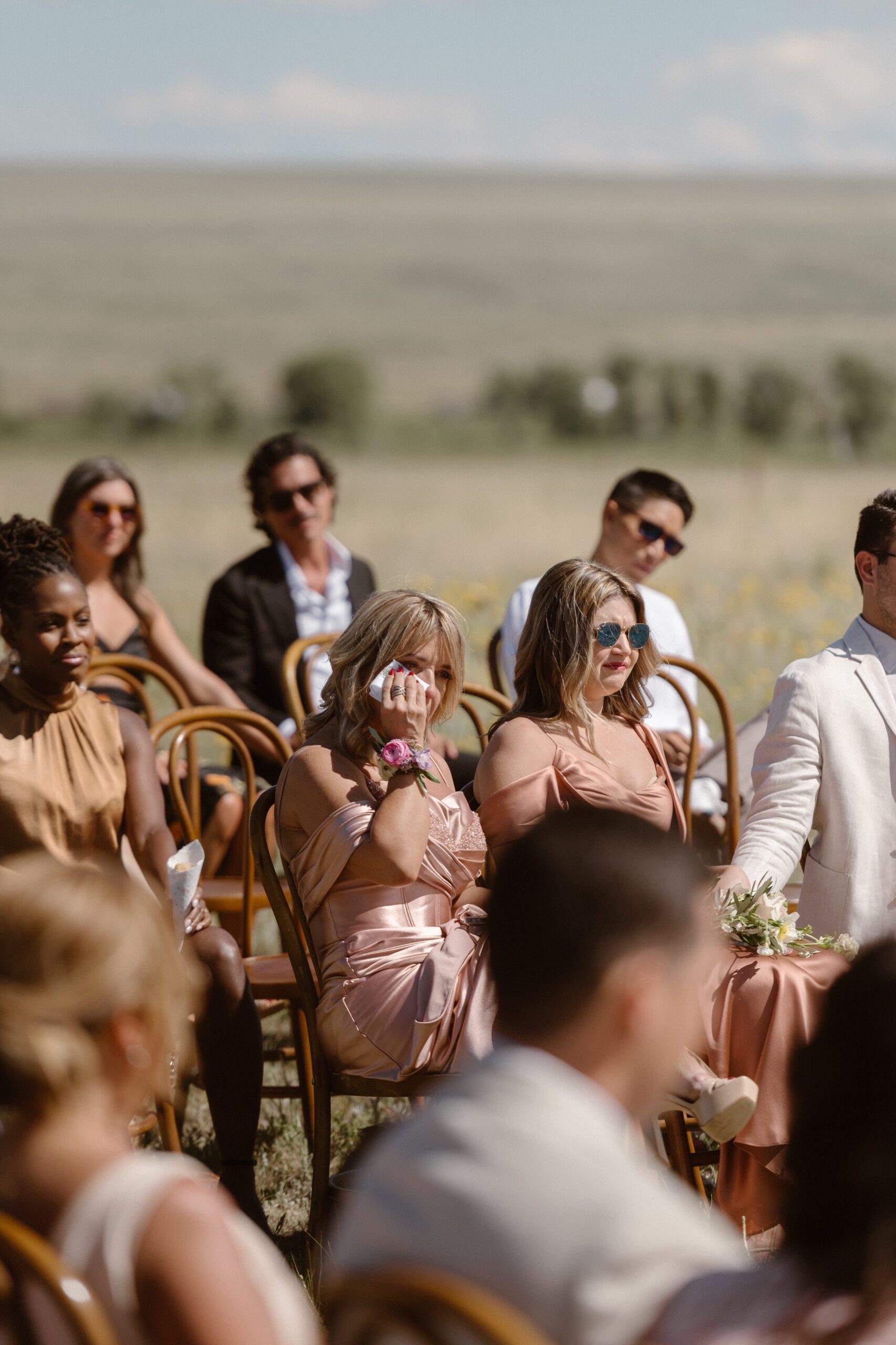 A photo of wedding guests crying at an outdoor wedding at Three Peaks Ranch. Photo by Colorado wedding photographer Ashley Joyce.