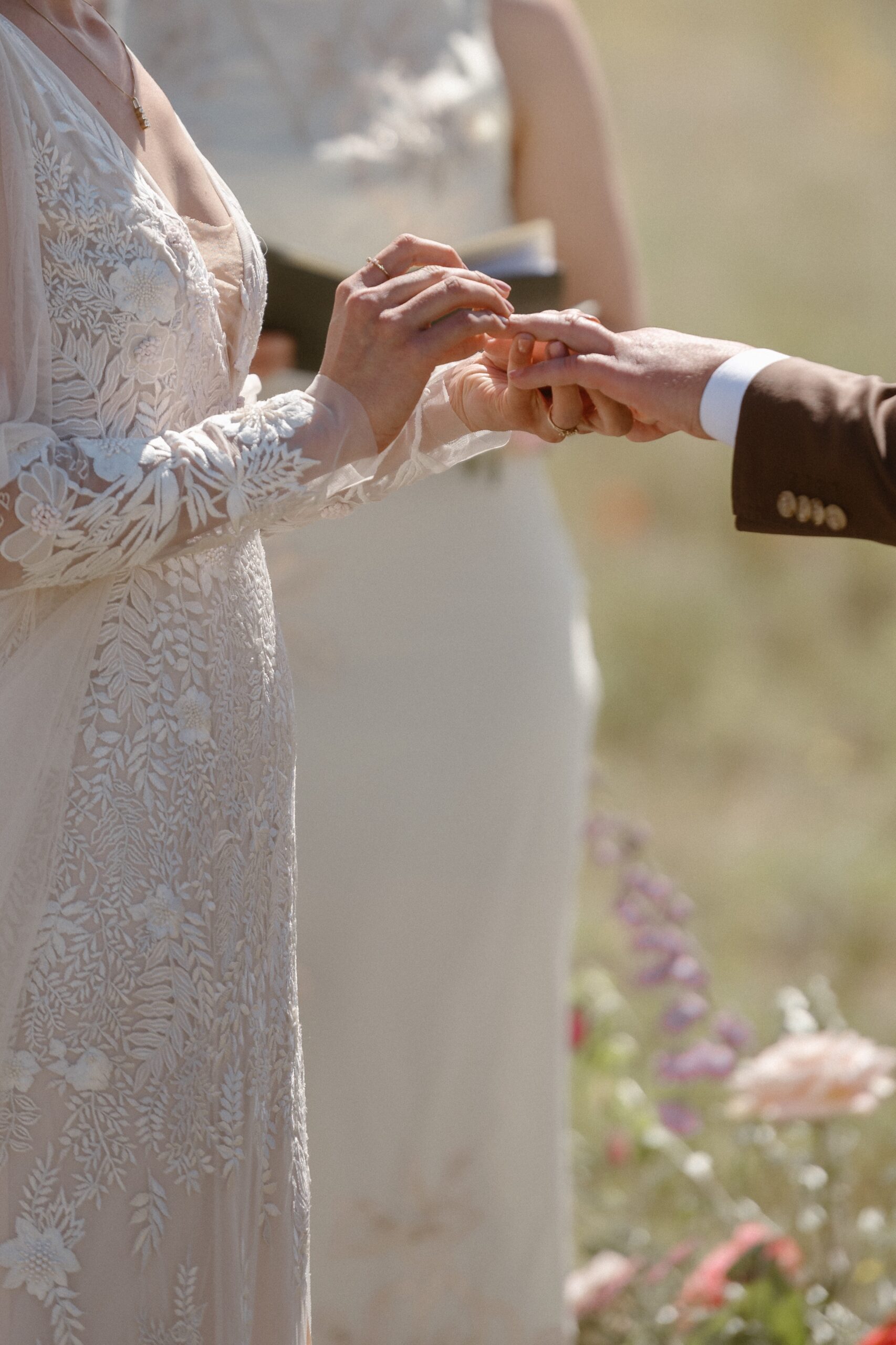 A closeup of a bride putting a wedding ring on her husbands ring finger at Three Peaks Ranch. Photo by Colorado wedding photographer Ashley Joyce.