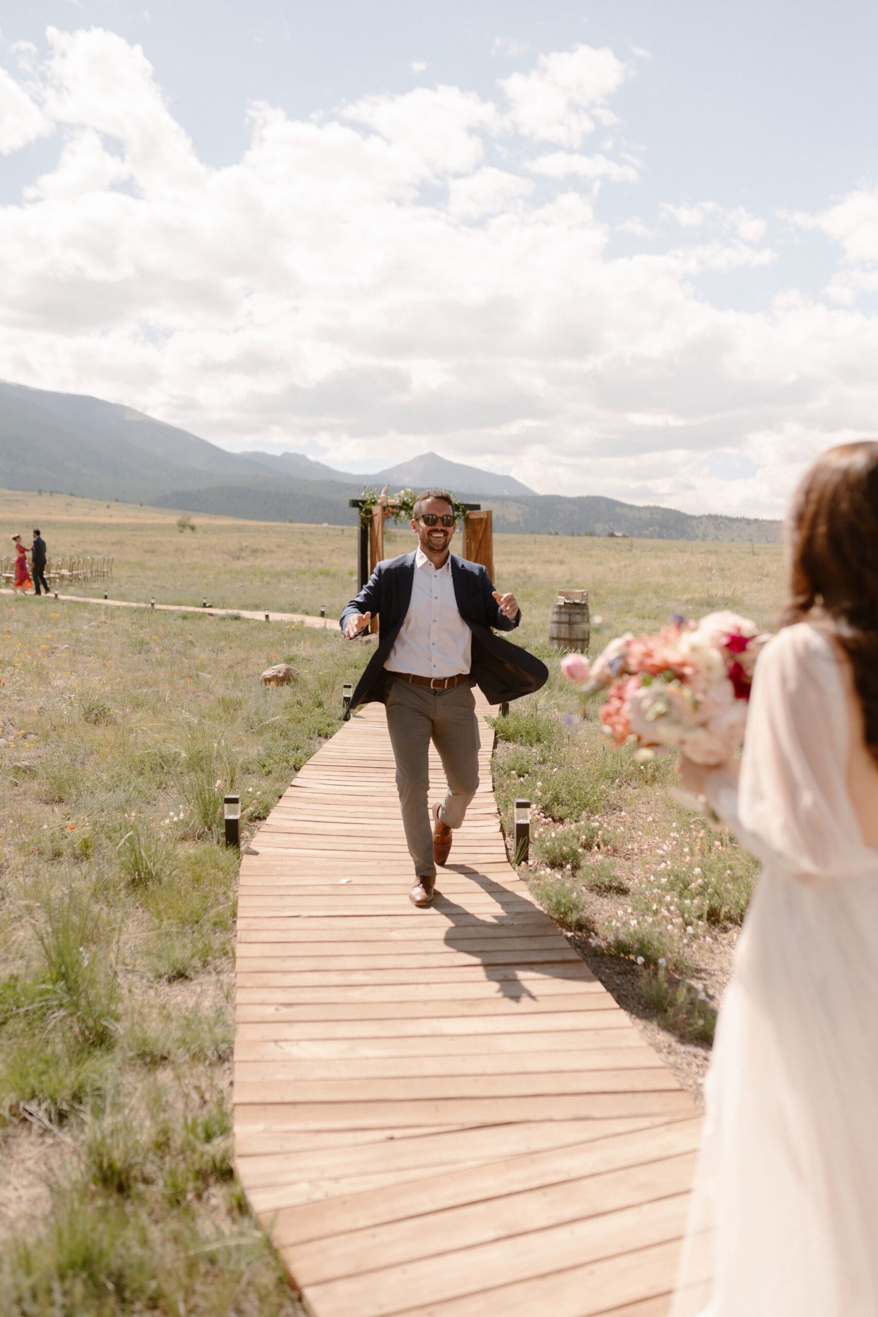 A wedding guests walks with his arms outstretch to the bride. Photo by Colorado wedding photographer Ashley Joyce.