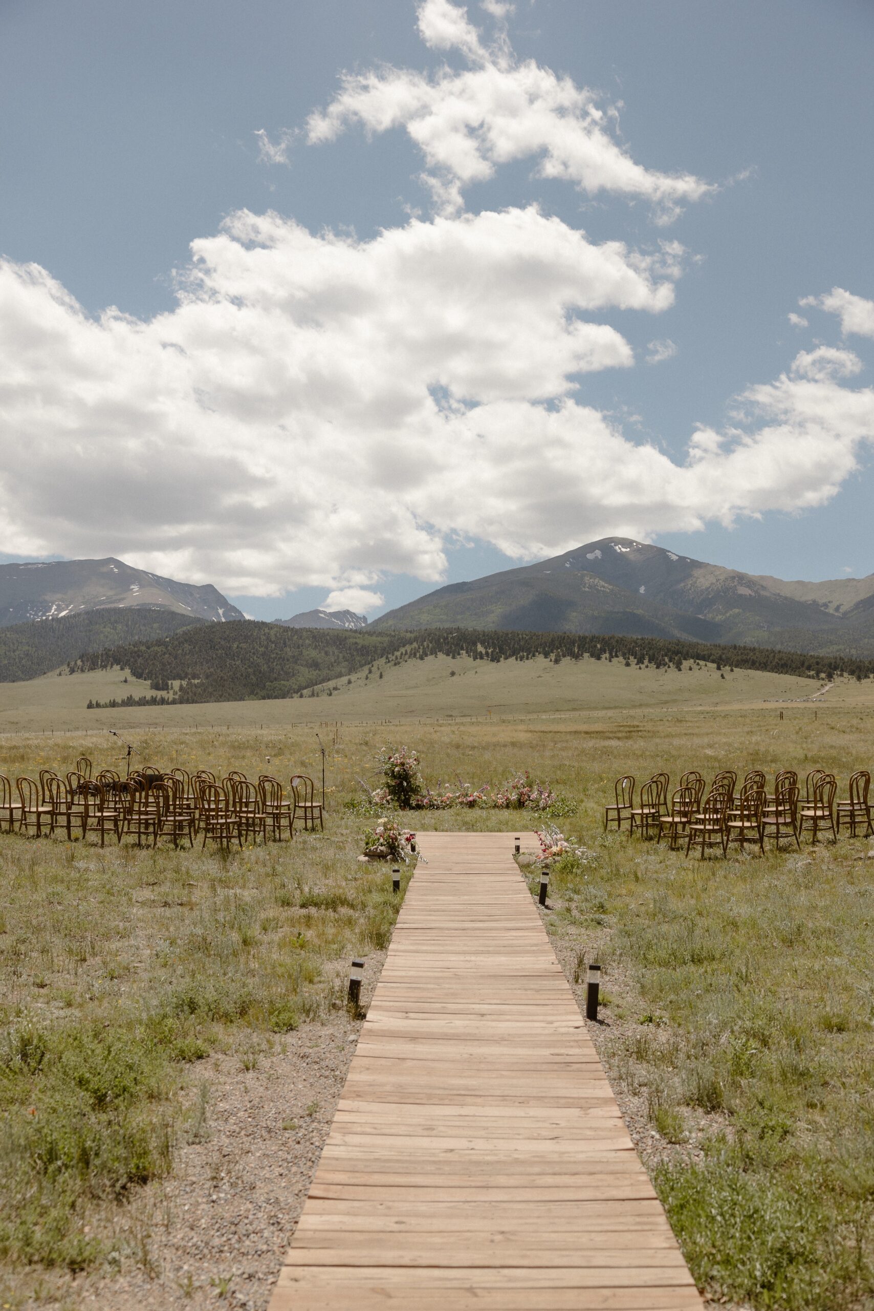 A photo of a wooden walkway leading to an outdoor ceremony setup for a Three Peaks Ranch wedding. Photo by Ashley Joyce.