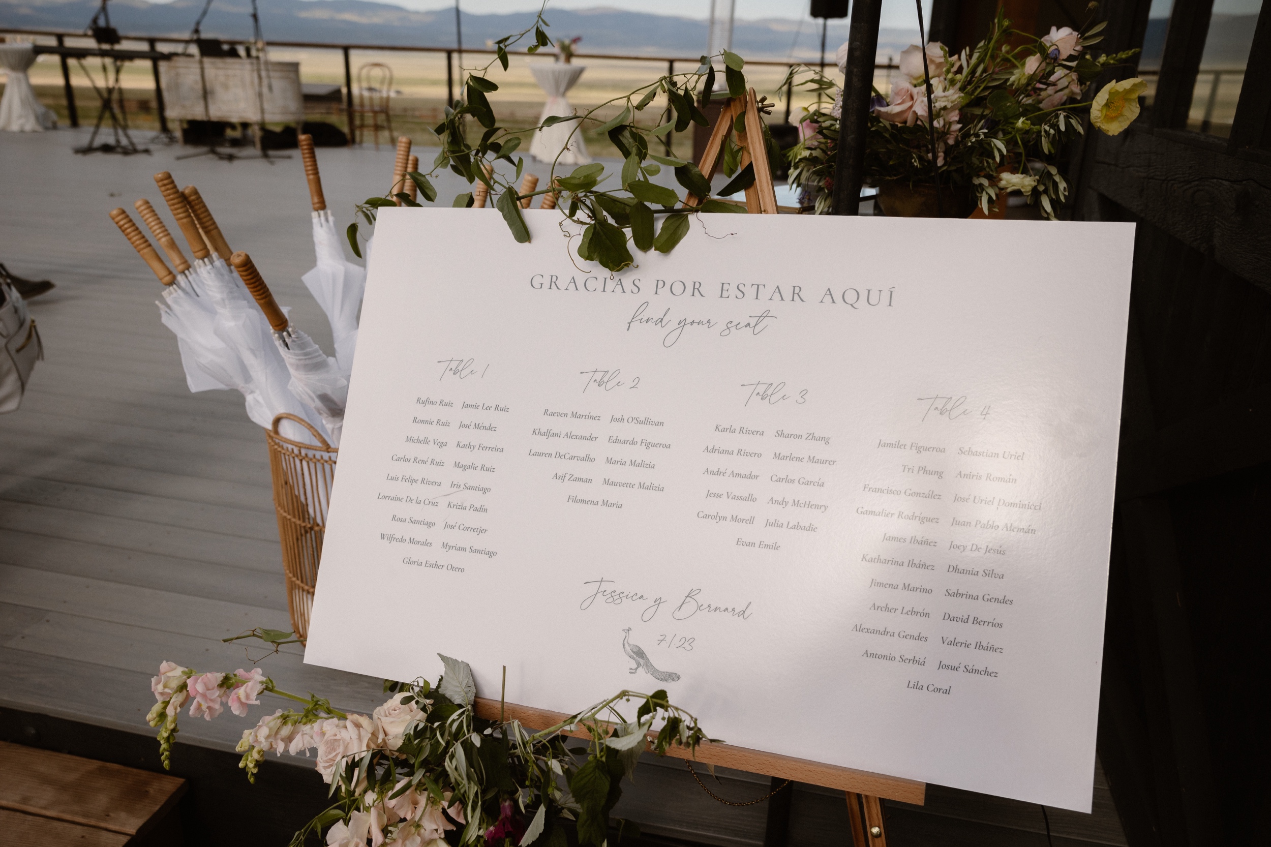 A photo of a seating chart surrounded by greenery and flowers at Three Peaks Ranch. Photo by Ashley Joyce.