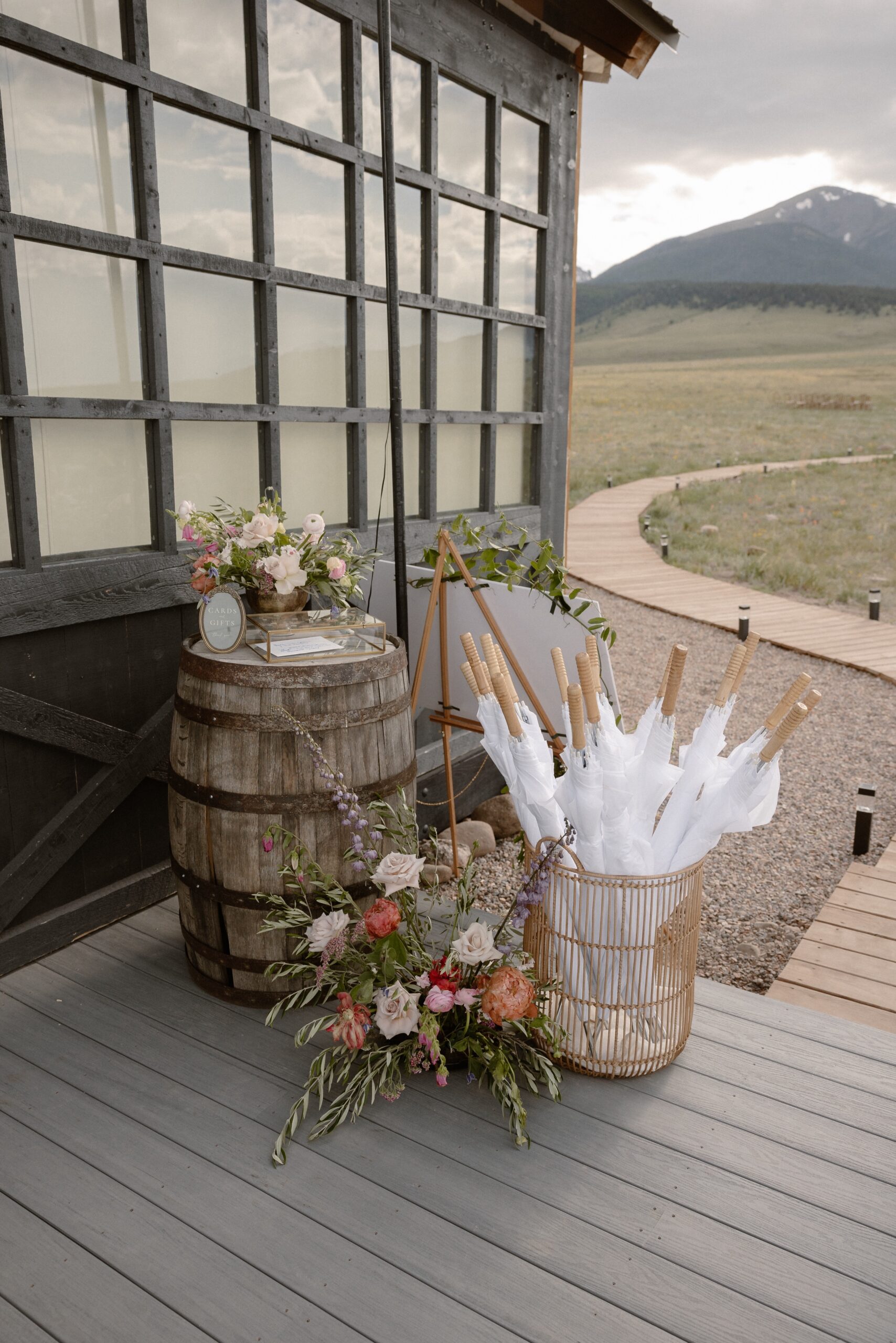 A photo of white umbrellas and other wedding guest accessories on the patio at Three Peaks Ranch. Photo by Ashley Joyce.