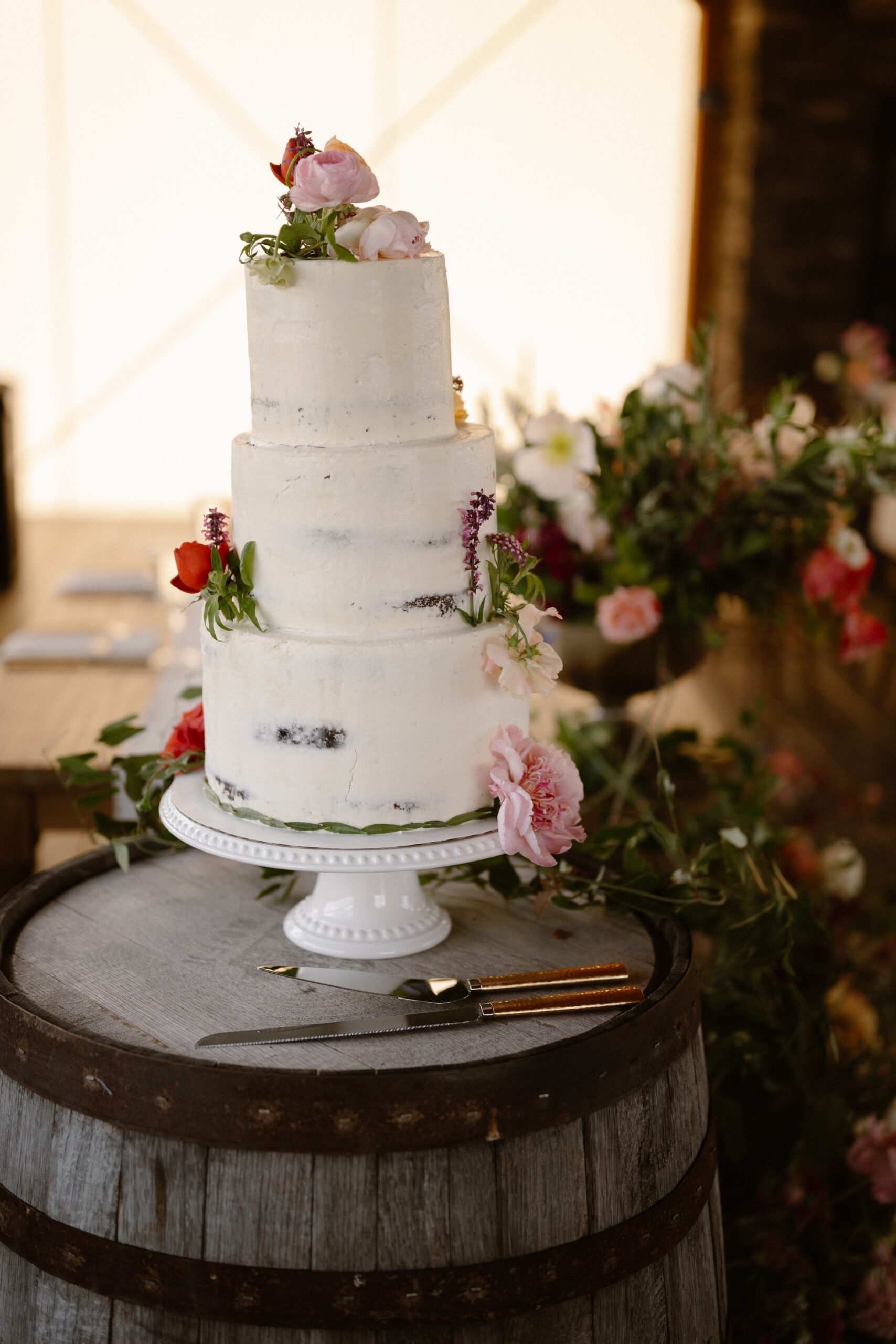 A photo of a white three tier cake at the wedding reception of Jessica and Bernard at their Three Peaks Ranch wedding. Photo by Ashley Joyce.