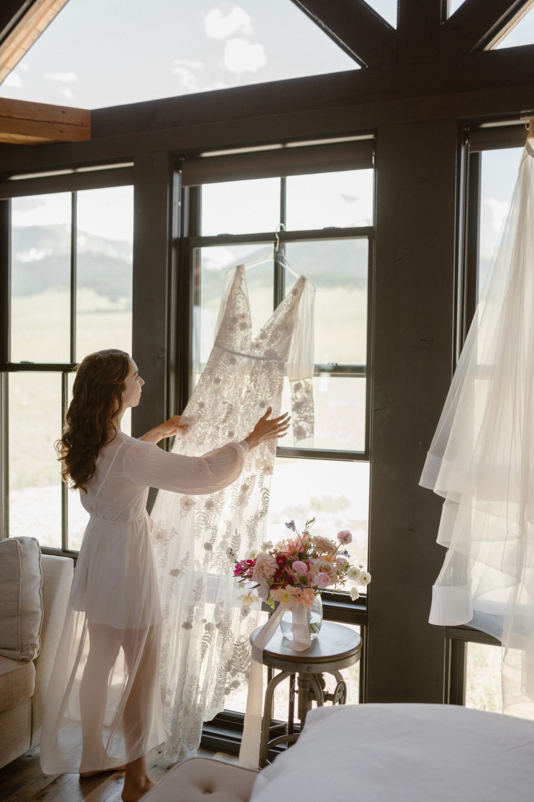 Bride Jessica displays her white wedding dress in the window at Three Peaks Ranch. Photo by Ashley Joyce.