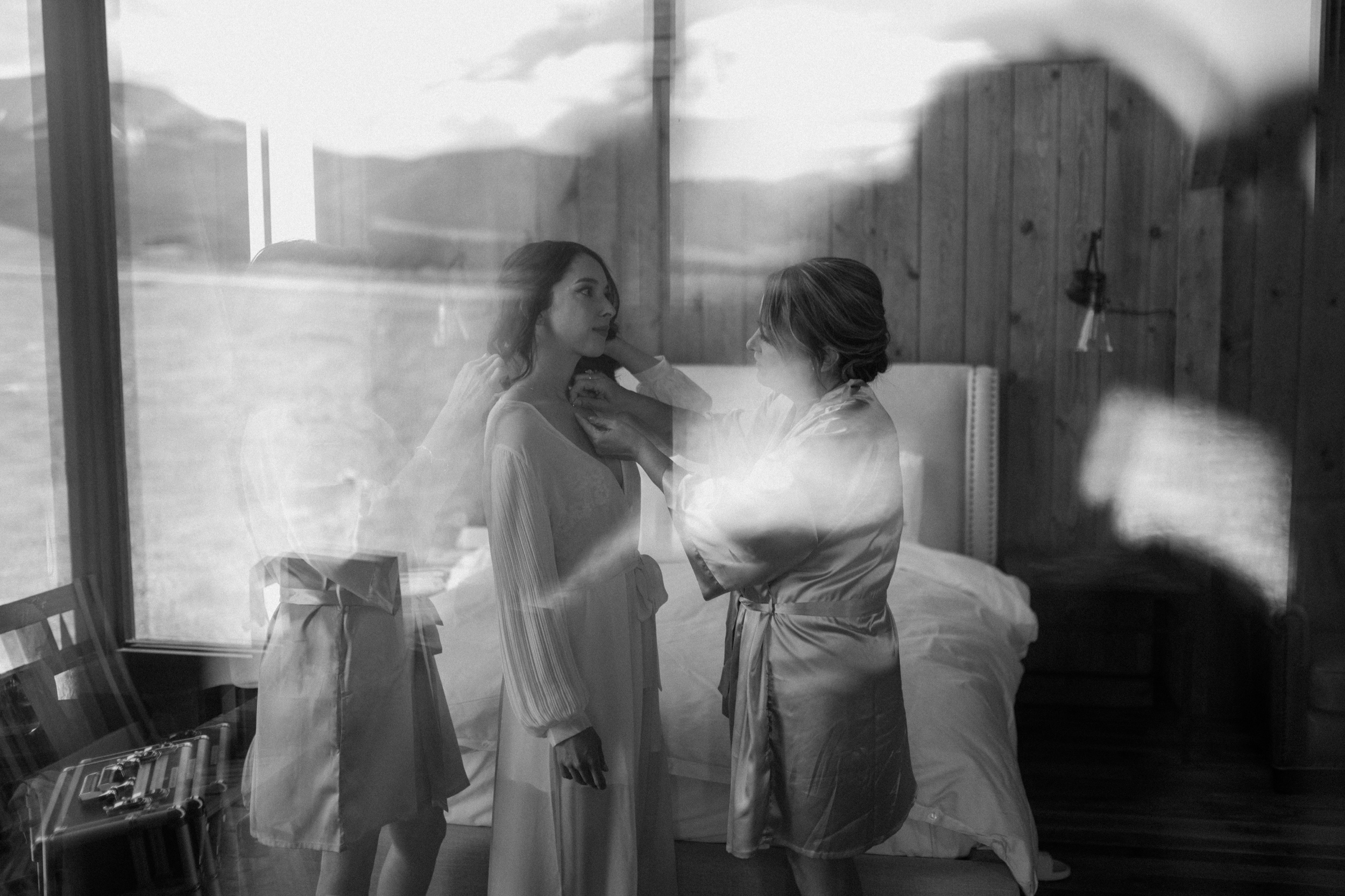 A black and white photo of bride getting help from family members while she gets ready for her wedding at Three Peaks Ranch. Photo by Ashley Joyce.