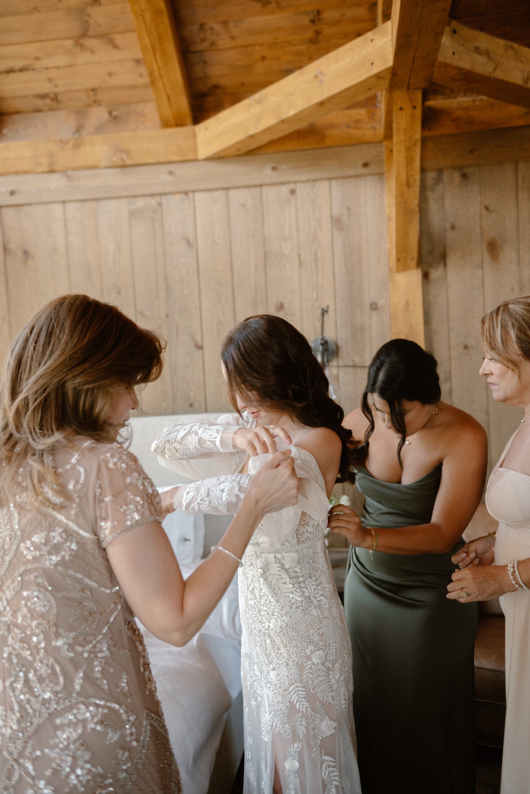 Bride Jessica gets in her wedding dress with the help of her family members at Three Peaks Ranch. Photo by Ashley Joyce.
