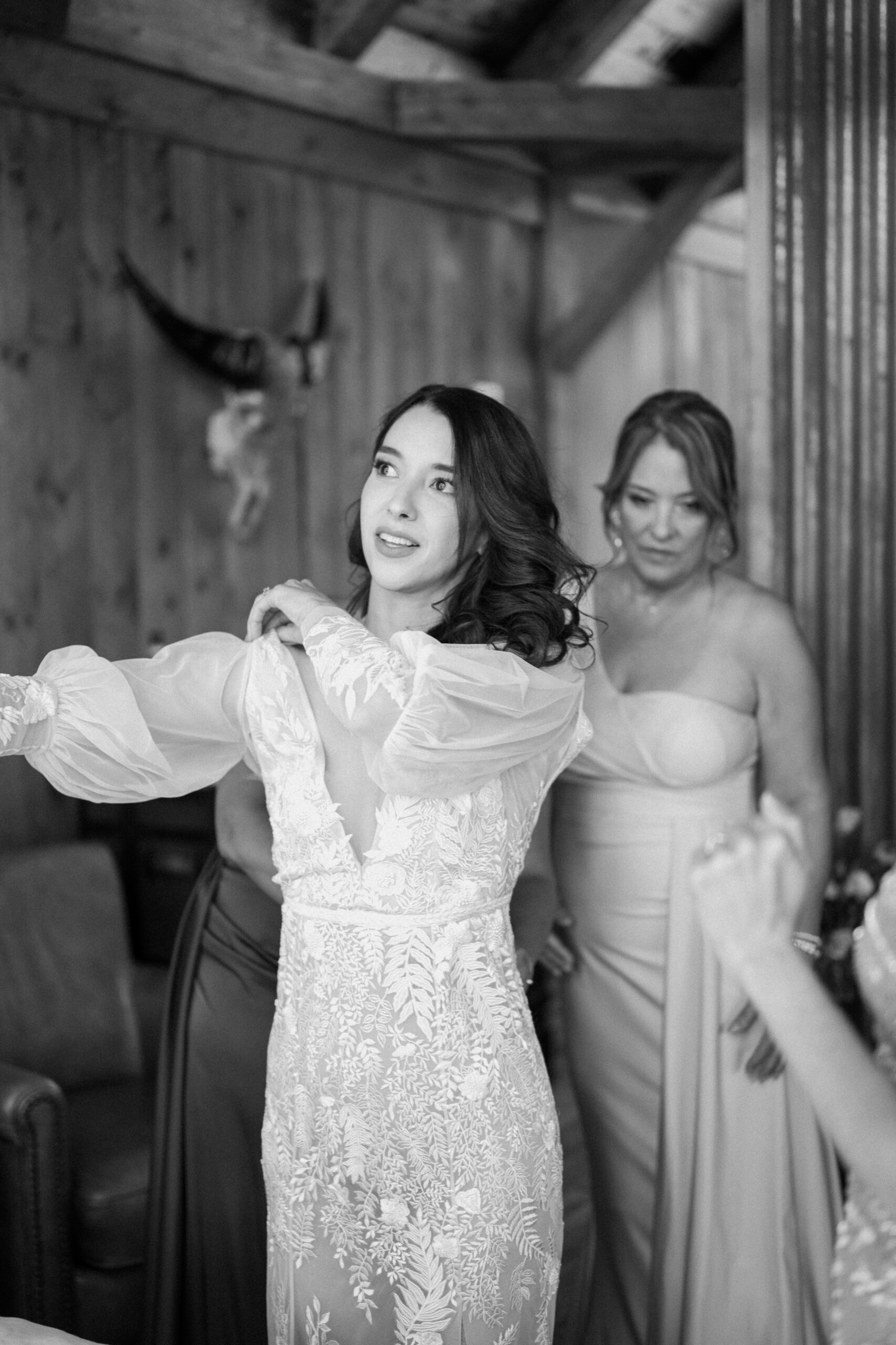A black and white photo of a bride getting in her wedding dress. Photo by Ashley Joyce.