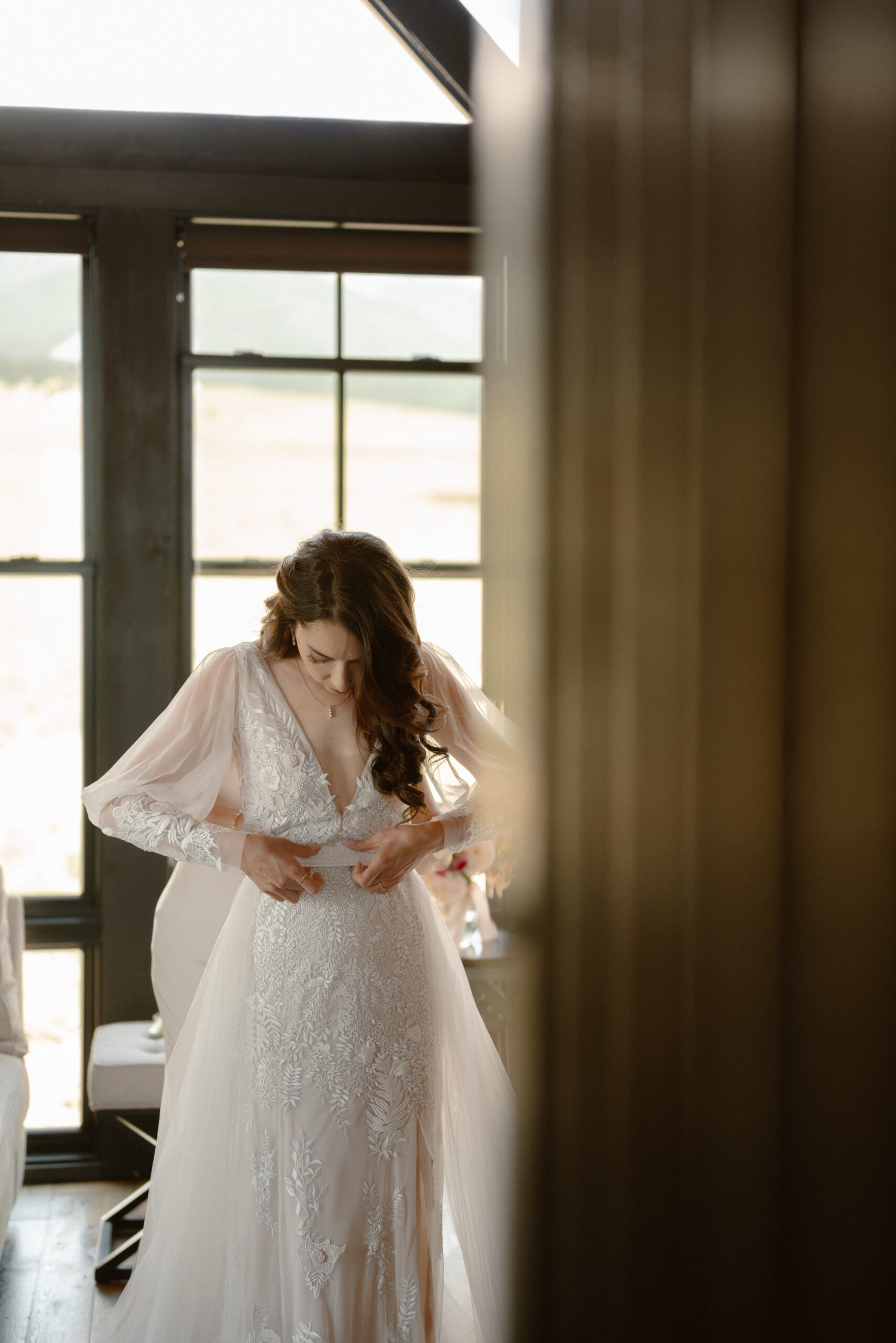 A photo of a bride getting her wedding dress put on at Three Peaks Ranch. Photo by Ashley Joyce.