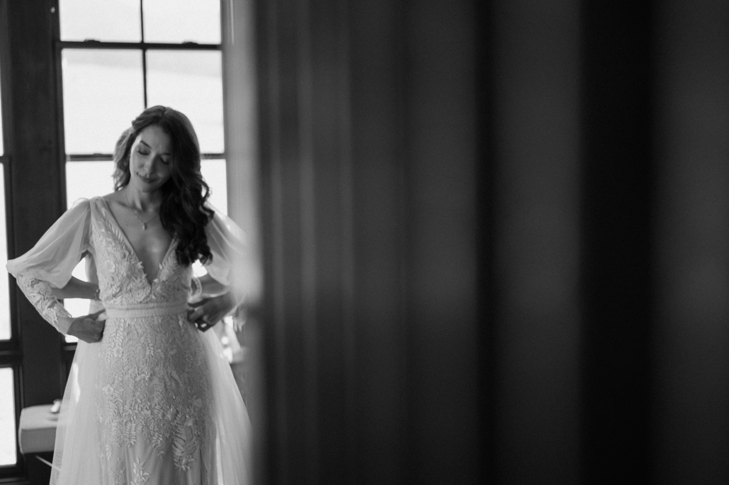 A black and white photo of a bride getting her wedding dress put on at Three Peaks Ranch. Photo by Ashley Joyce.