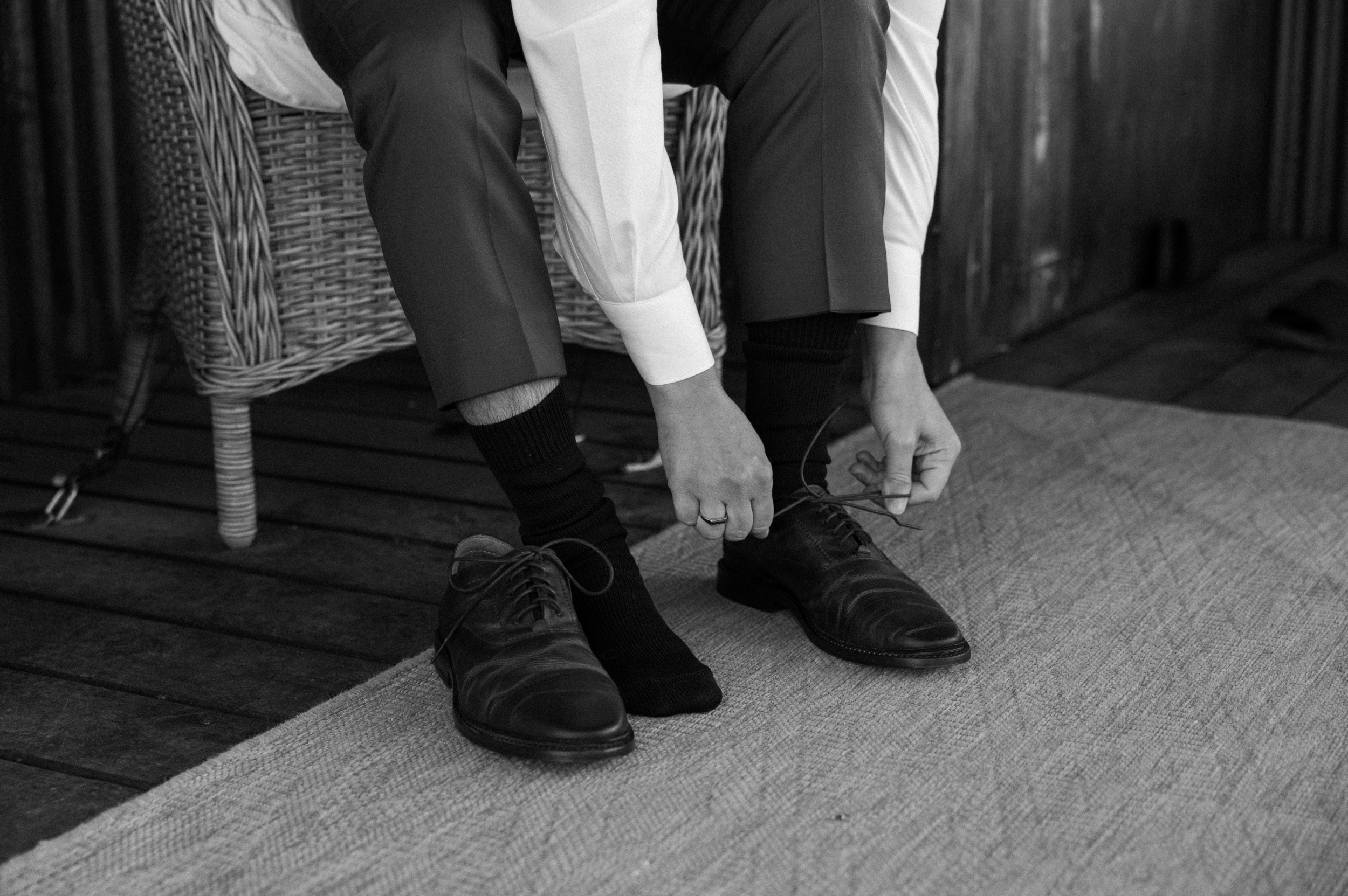 A black and white photo of a groom tying his shoes. Photo by Colorado wedding photographer Ashley Joyce.