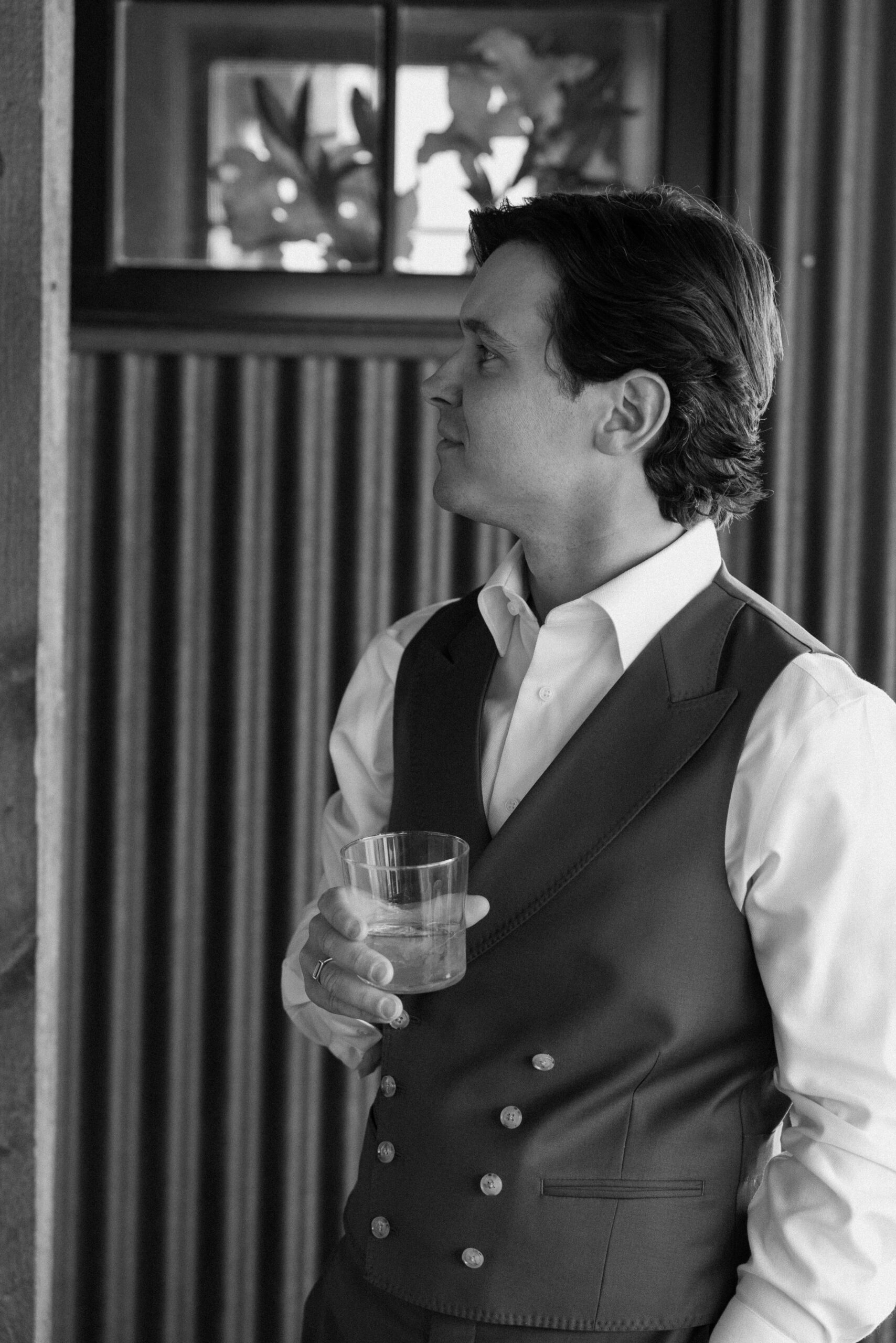 A black and white photo of a groom posing with his rum for his groom portraits at Three Peaks Ranch. Photo by Colorado wedding photographer Ashley Joyce.