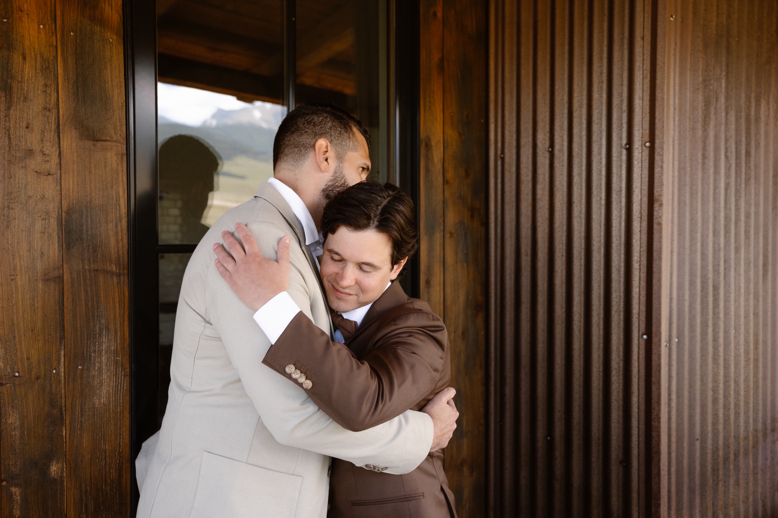 A photo of a groom and one of his groomsmen hugging each other. Photo by Colorado wedding photographer Ashley Joyce.