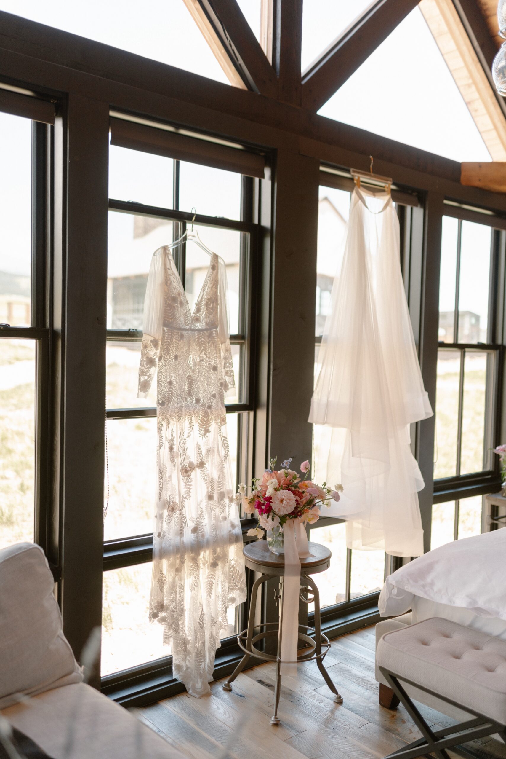 A photo of a bride's dresses hanging on the window sill at Three Peaks ranch. Photo by Ashley Joyce.