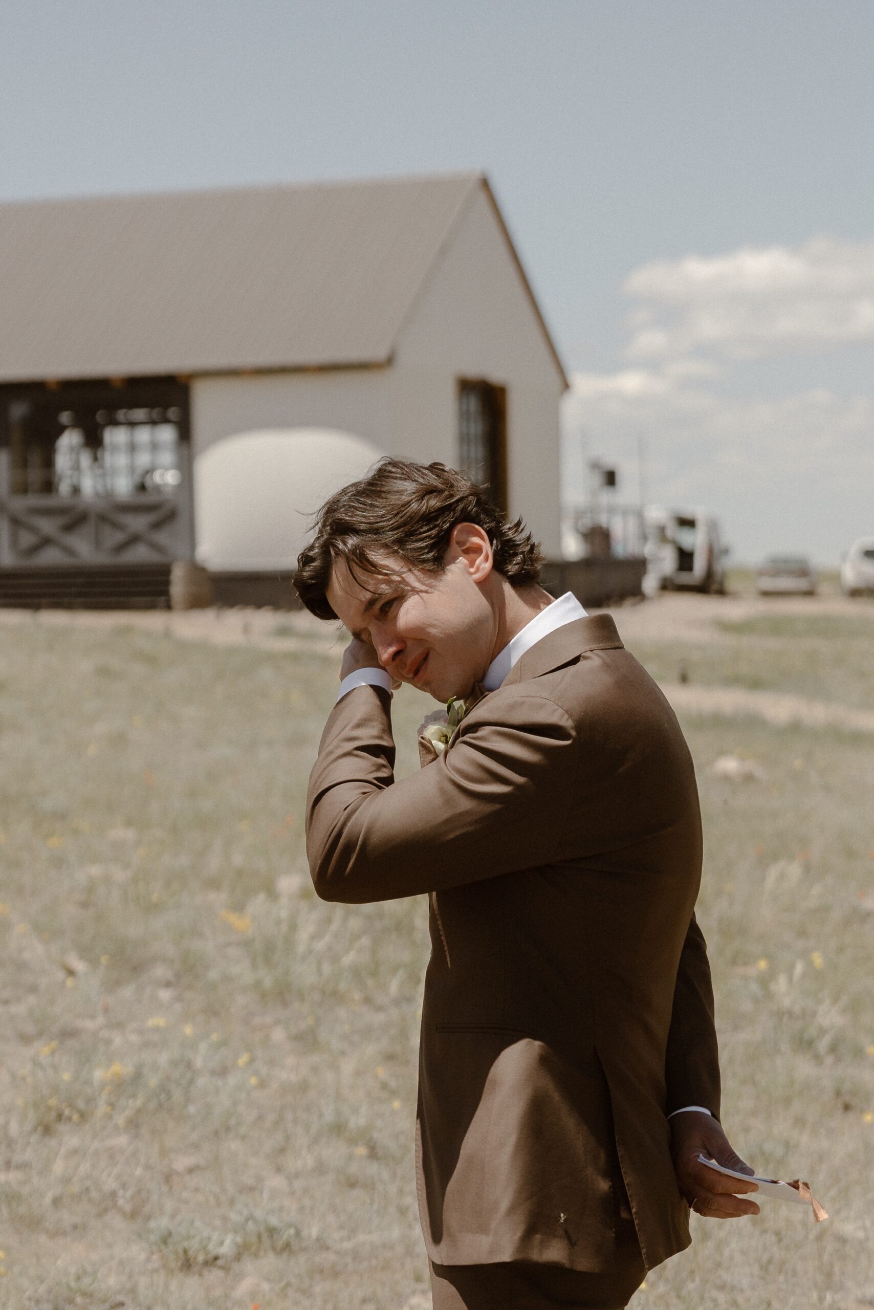 A groom wipes his eyes as he cries upon seeing his bride. Photo by Colorado wedding photographer Ashley Joyce.