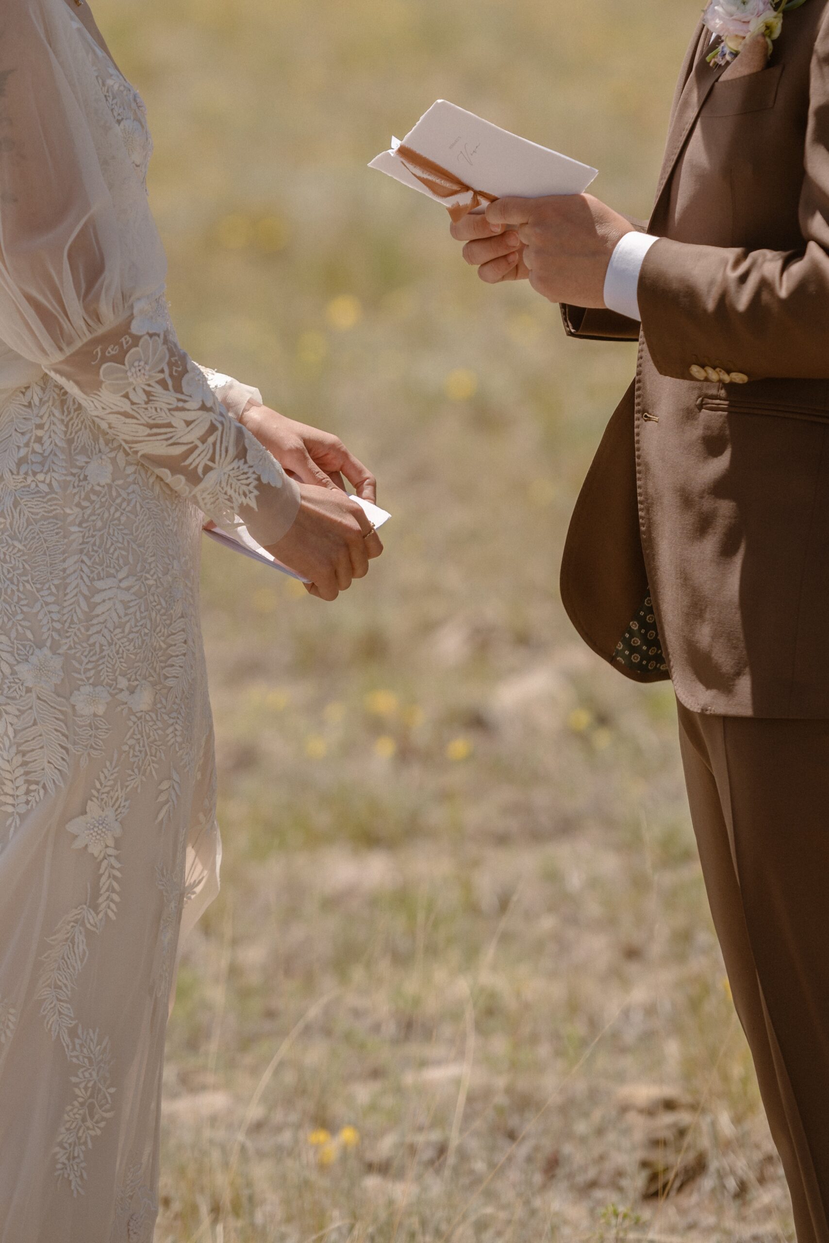 A closeup of a groom holding his vow book and a bride holding her vow book at Three Peaks Ranch. Photo by Ashley Joyce.