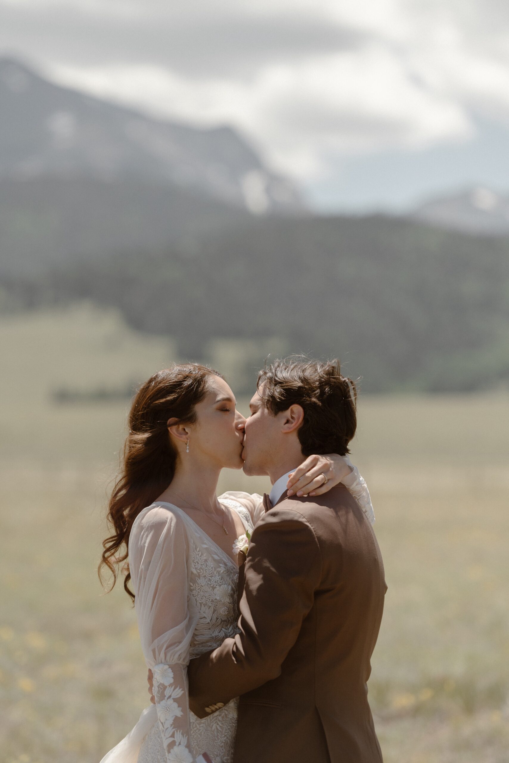 A bride and groom kiss one another as they embrace after they say their vows to one another at Three Peaks Ranch. Photo by Colorado wedding photographer Ashley Joyce.