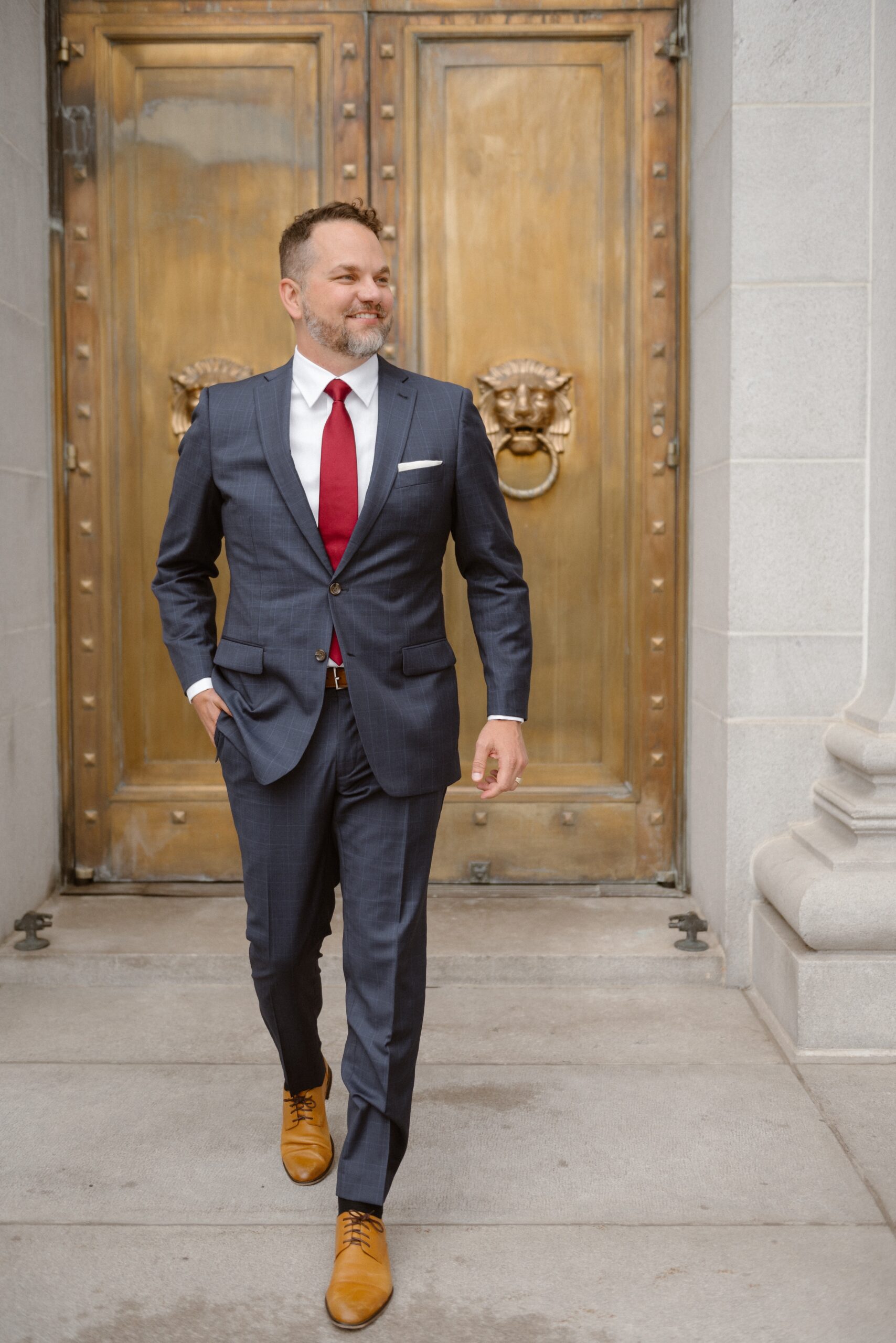 A groom poses in front of a golden door for his wedding portraits. Photo by Colorado wedding photographer Ashley Joyce.
