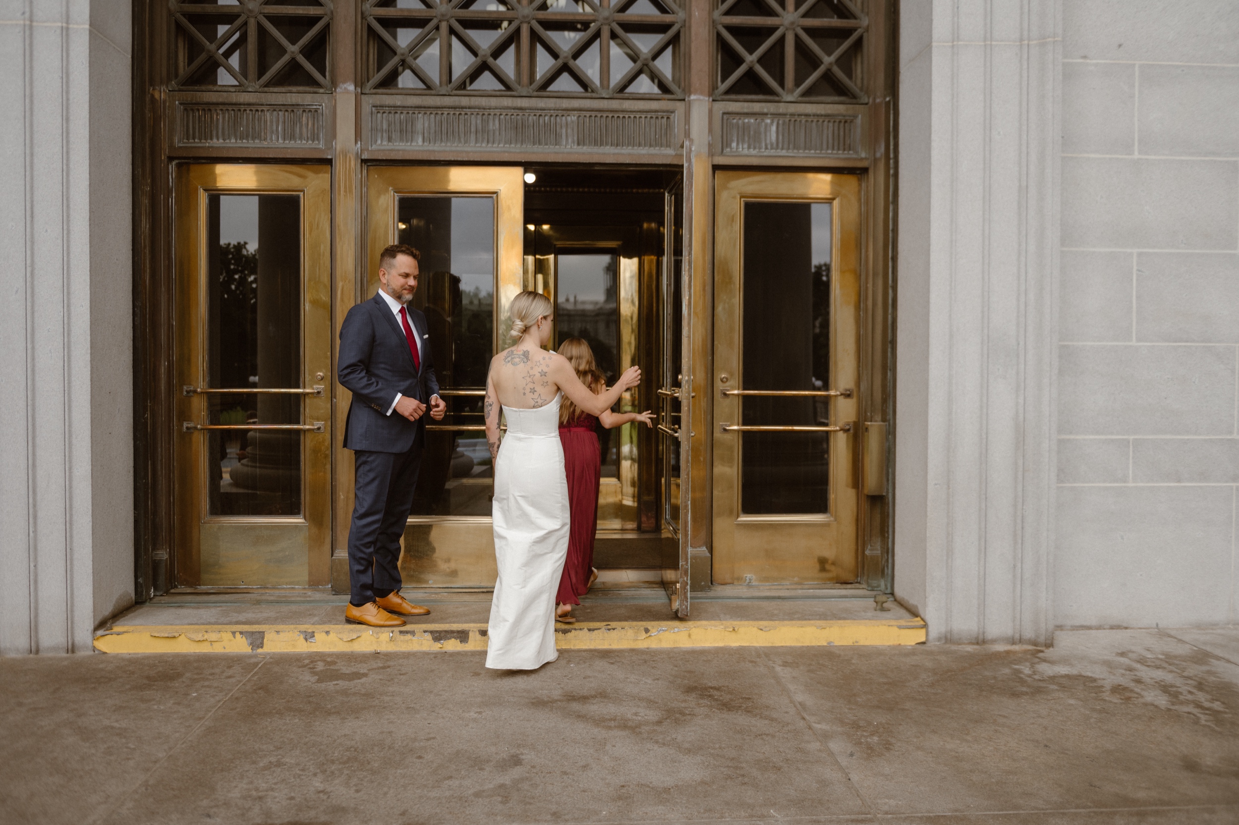 A candid photo of a bride and groom and a few of their wedding guests enter the Denver courthouse for their wedding. Photo by Colorado wedding photographer Ashley Joyce.