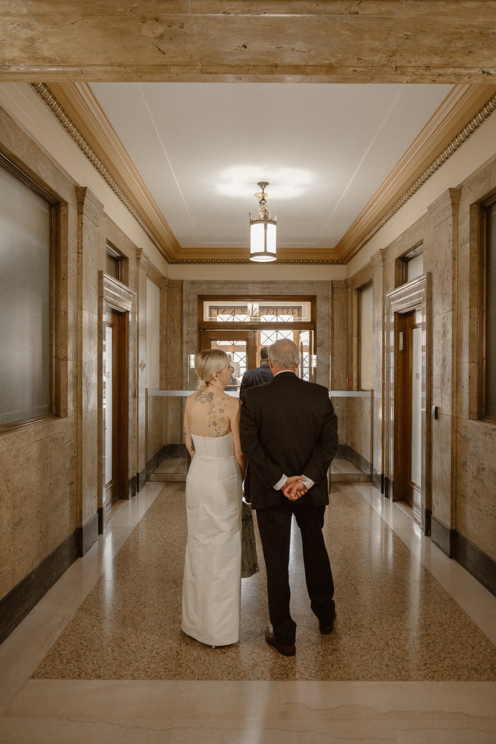 A bride stands in line to exit the Denver courthouse with her husband and family. Photo by Colorado wedding photographer Ashley Joyce.