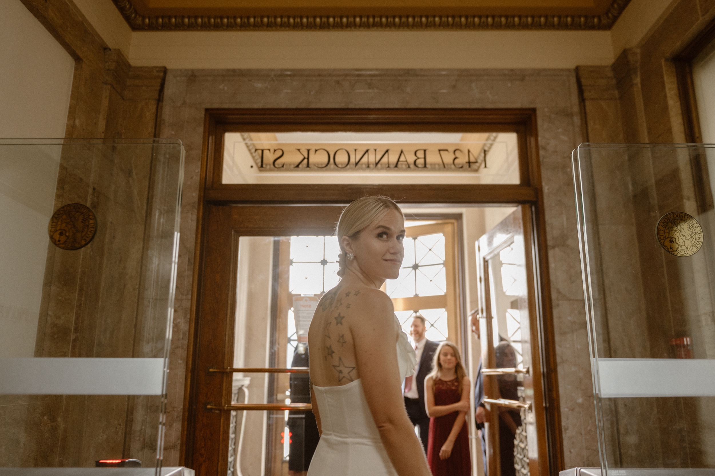A bride stands in line to exit the Denver courthouse with her husband and family. Photo by Colorado wedding photographer Ashley Joyce.
