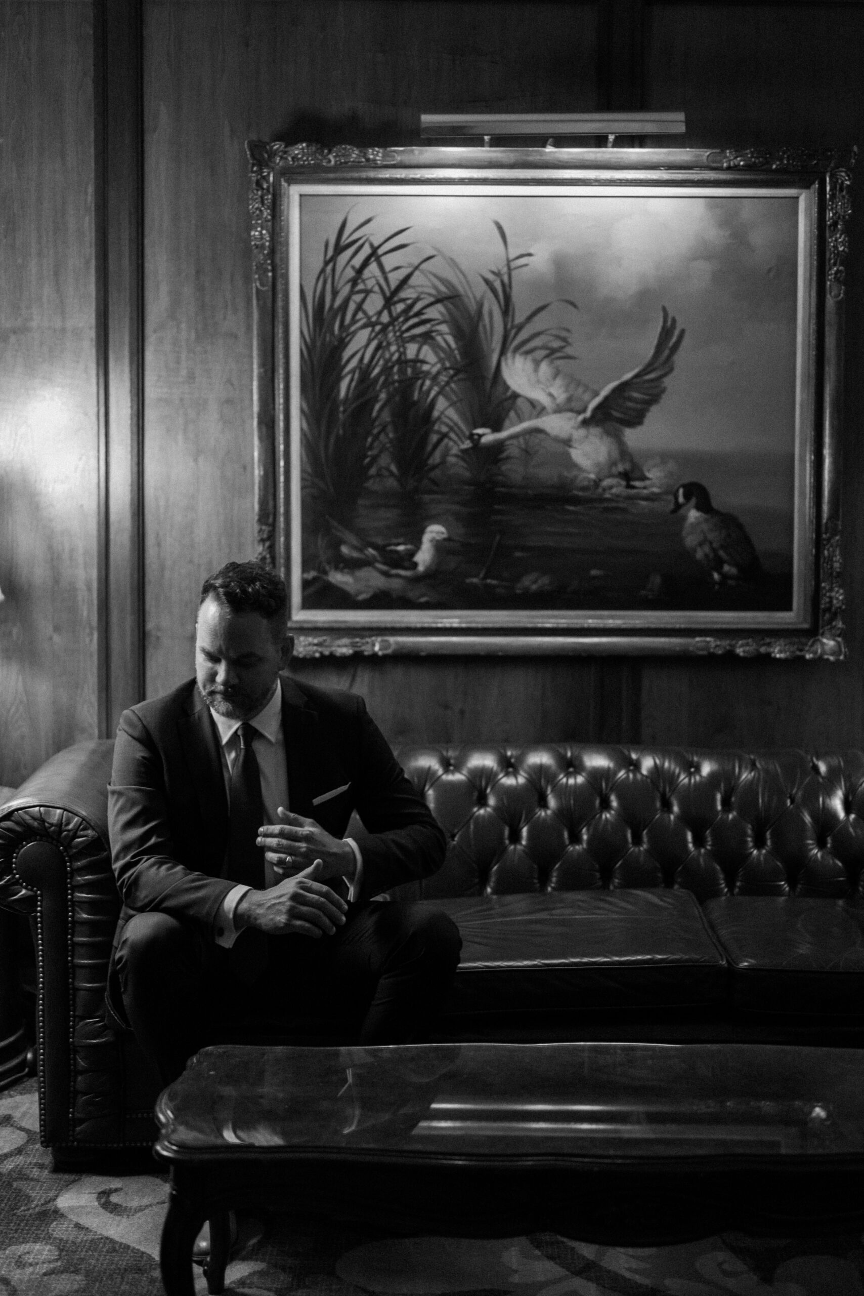 A groom poses for his wedding portraits on a couch at the Brown Palace. Photo by Colorado wedding photographer Ashley Joyce.