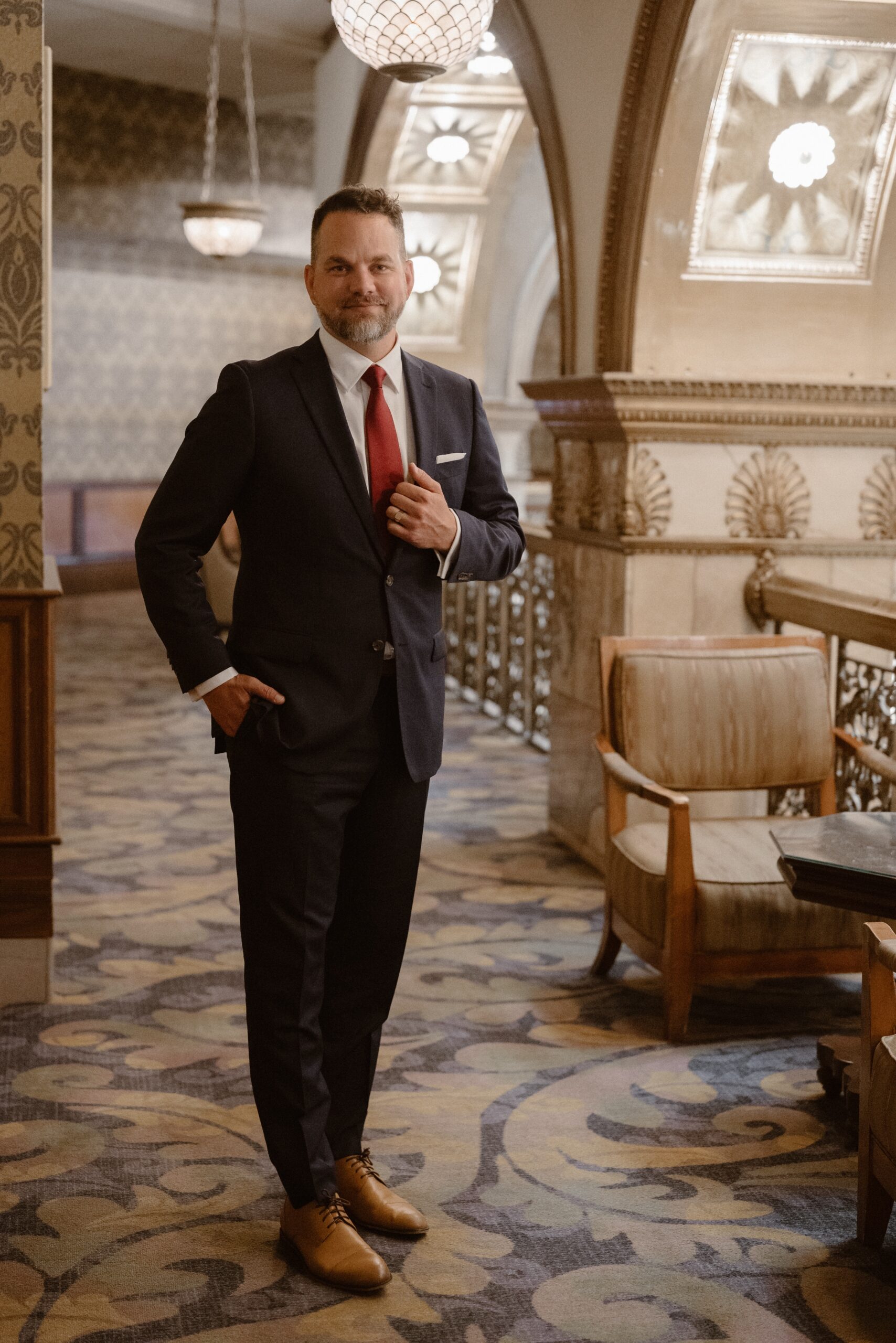 A groom poses for his wedding portraits at the Brown Palace. Photo by Colorado wedding photographer Ashley Joyce.