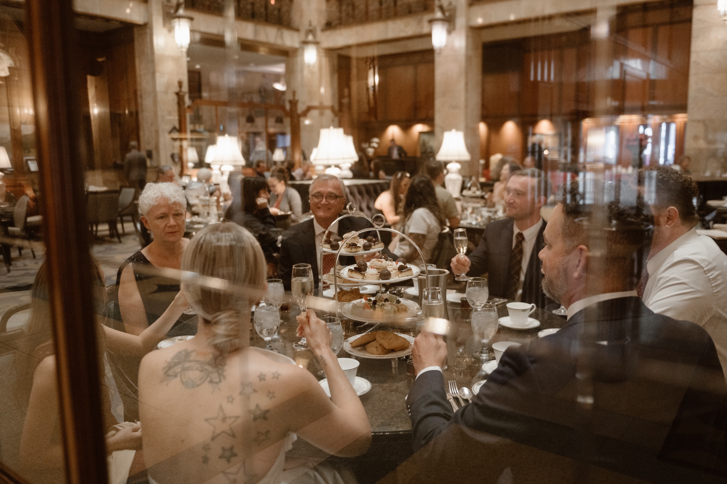 A bride and groom toast with their family members at their high tea wedding reception at the Brown Palace in Denver, Colorado. Photo by Denver wedding photographer Ashley Joyce.
